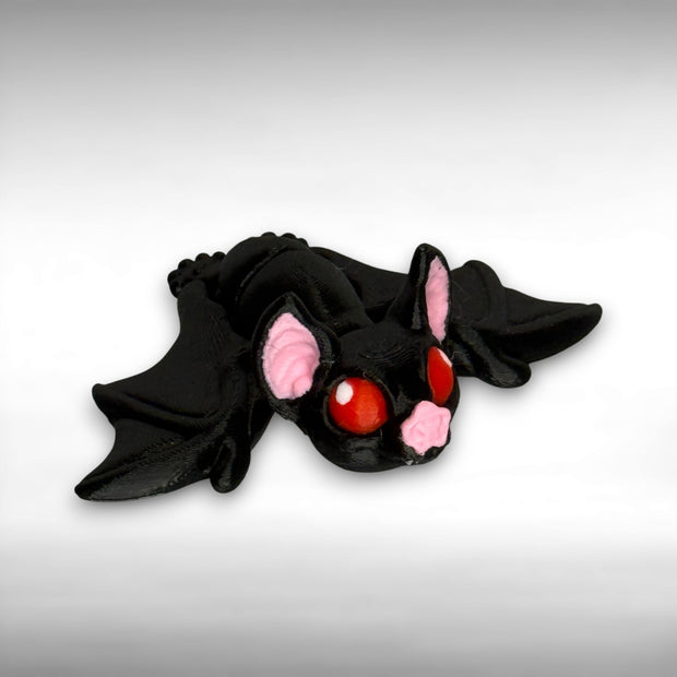Black bat-shaped figure with red eyes and pink ears on a gray background