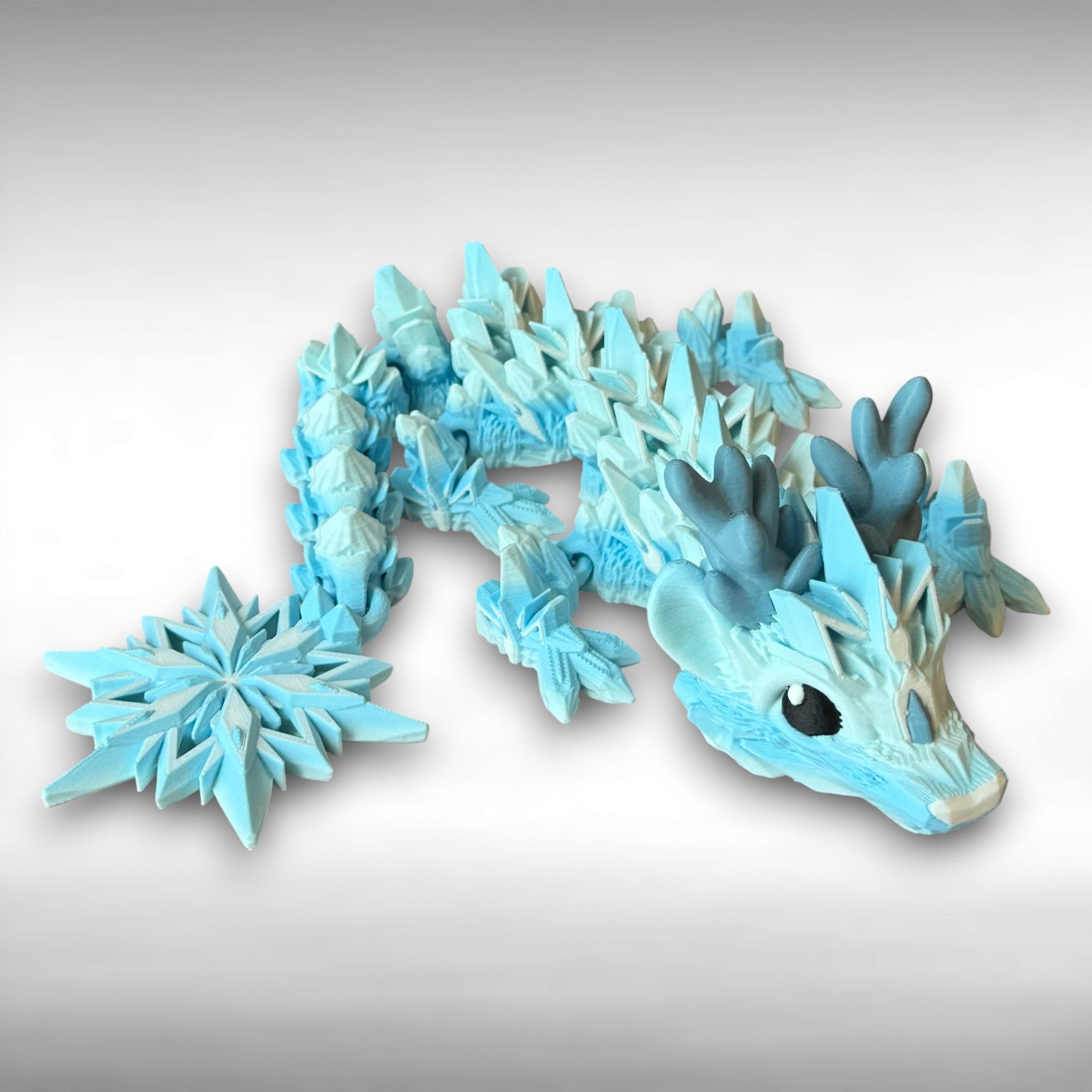 Blue dragon toy featuring a winter themed body with snowflake tail on a gray background