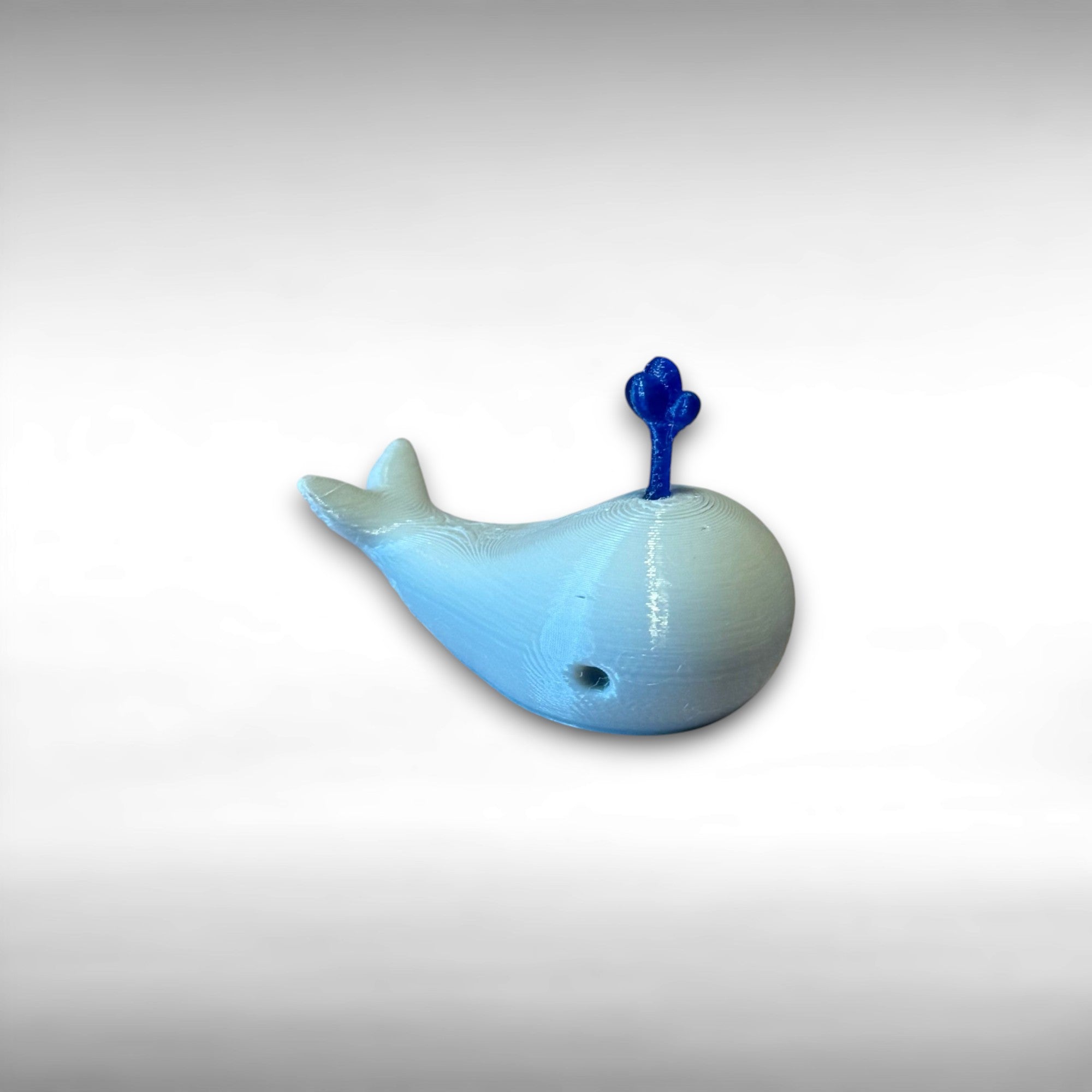 A 3D printed white whale chopstick rest with a space for holding chopsticks, placed on a wooden surface.