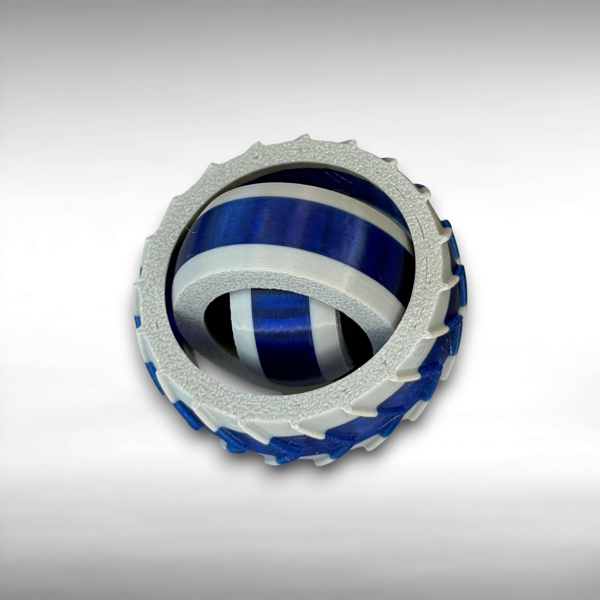 3D printed gray and blue rings set into each other that spin in different directions on a gray background