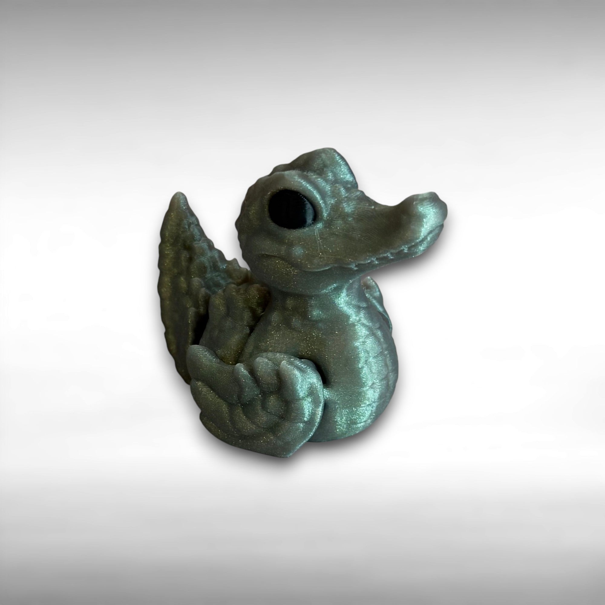 A 3D printed sparkly green figure with the body of a duck and the head of a crocodile against a white background