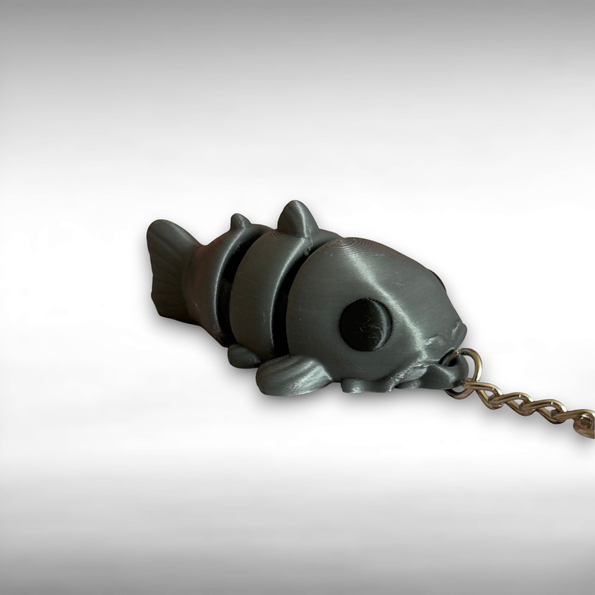 3D printed gray catfish-shaped keychain on a light gray background