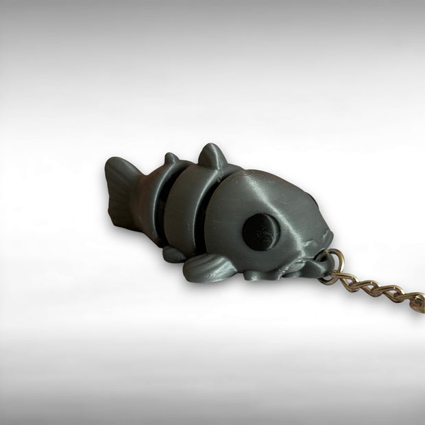 3D printed gray catfish-shaped keychain on a light gray background