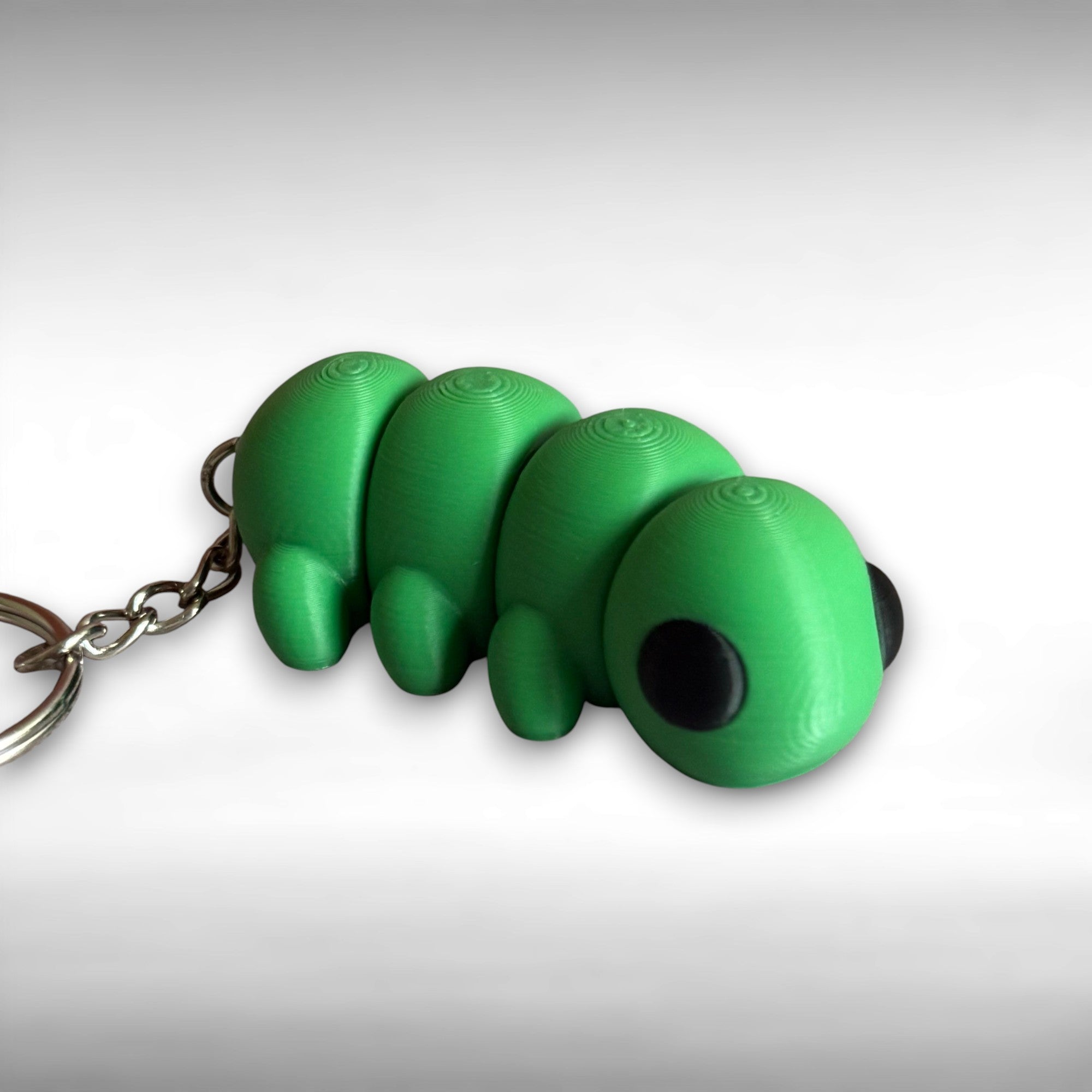 3D printed green caterpillar-shaped keychain on a white background