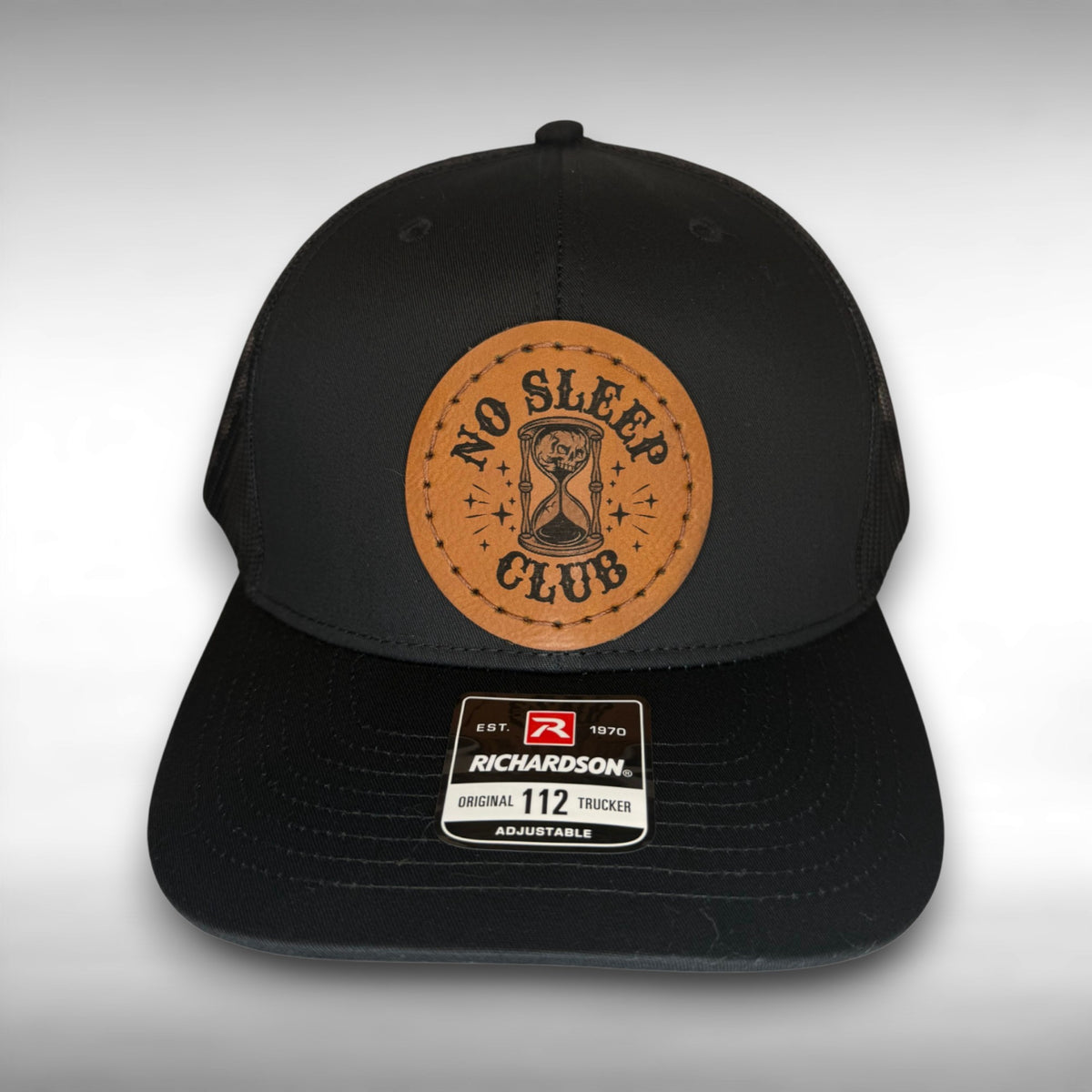 Black cap with a Richardson sticker and a brown leather patch featuring an hourglass and skull design with the phrase 