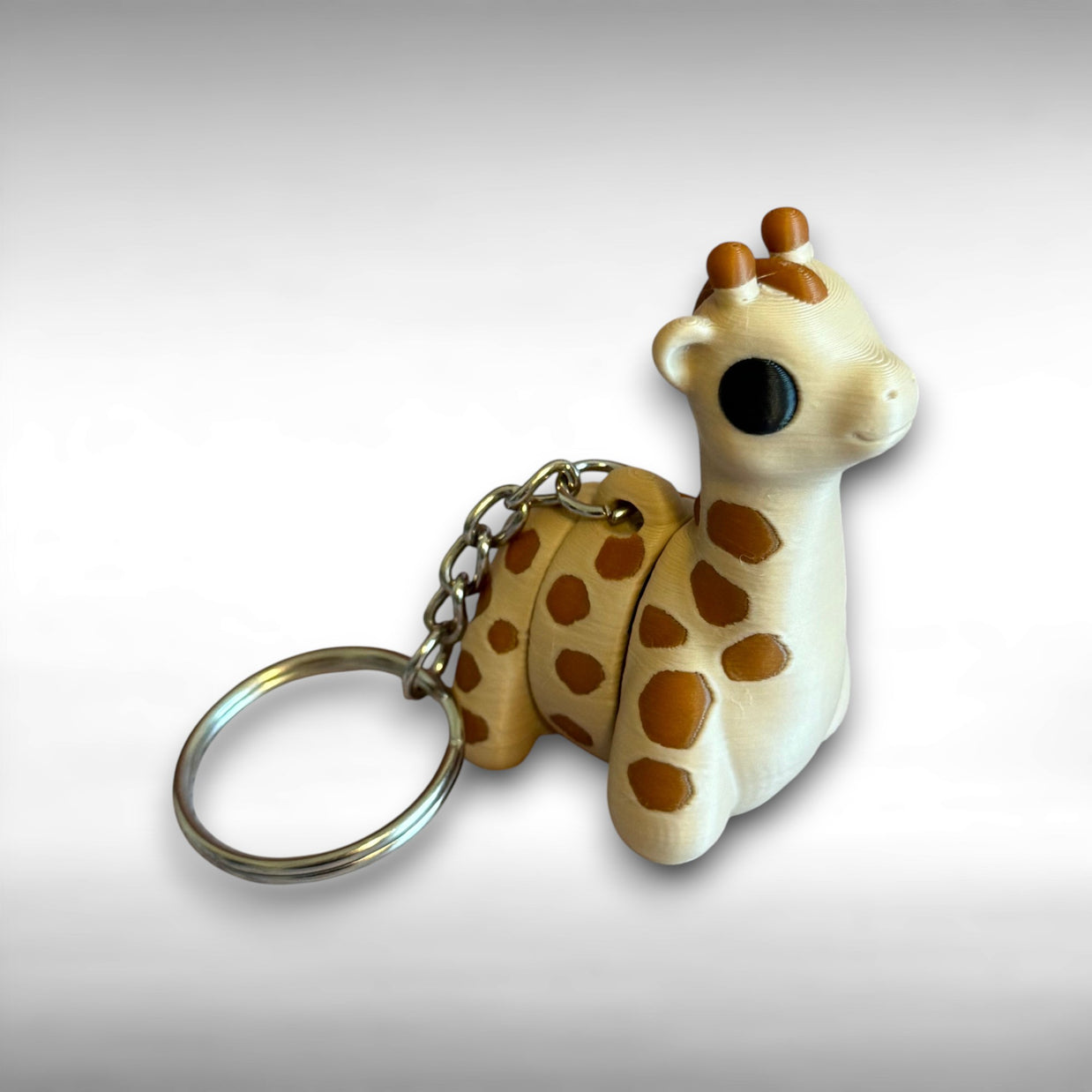3D printed beige and brown giraffe-shaped keychain on a light gray background