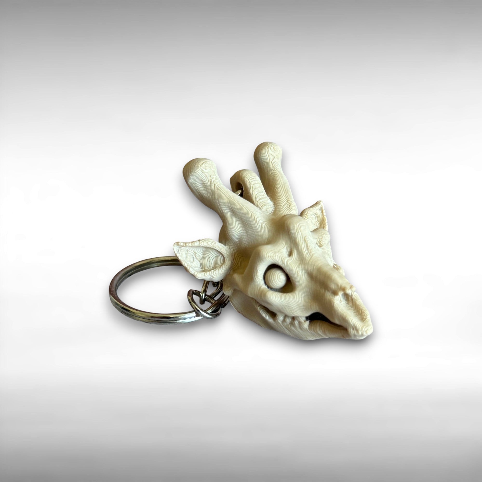3D printed beige giraffe skull keychain against a white background