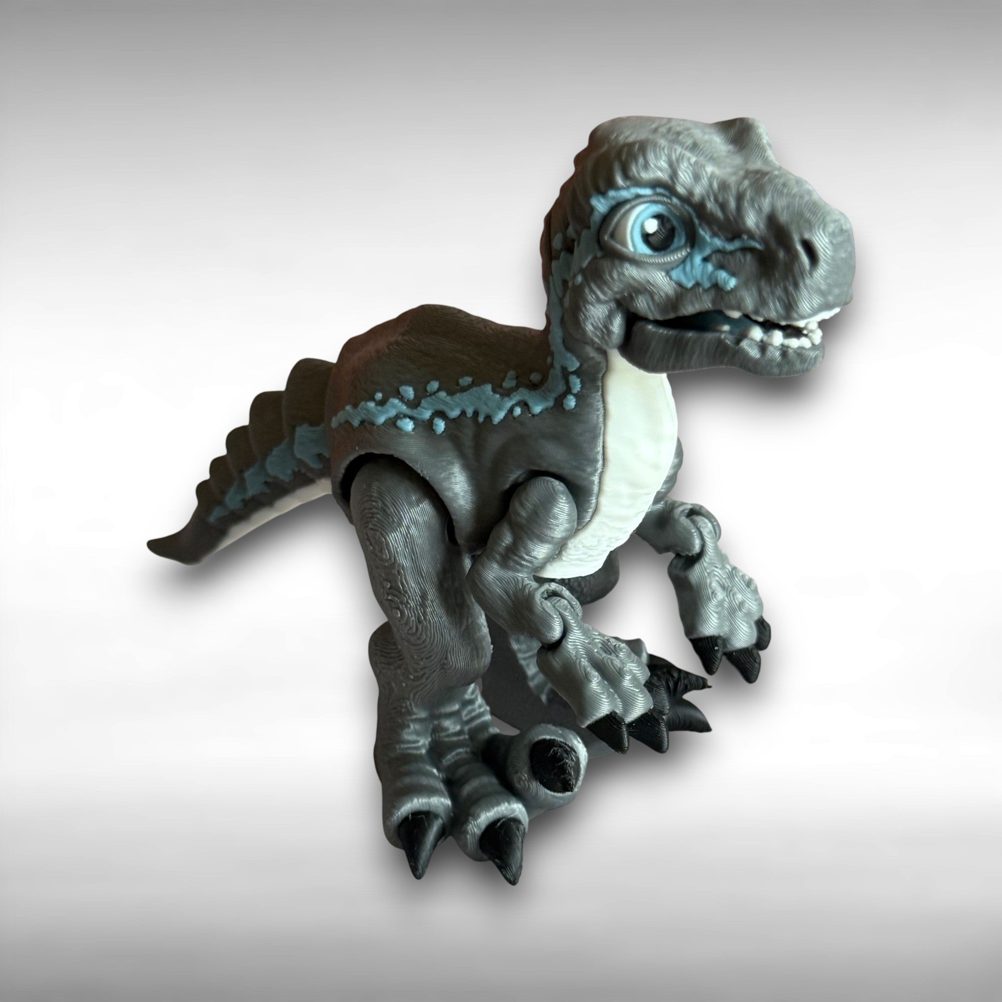 3D printed blue, gray, and white colored raptor dinosaur figure on a light gray background