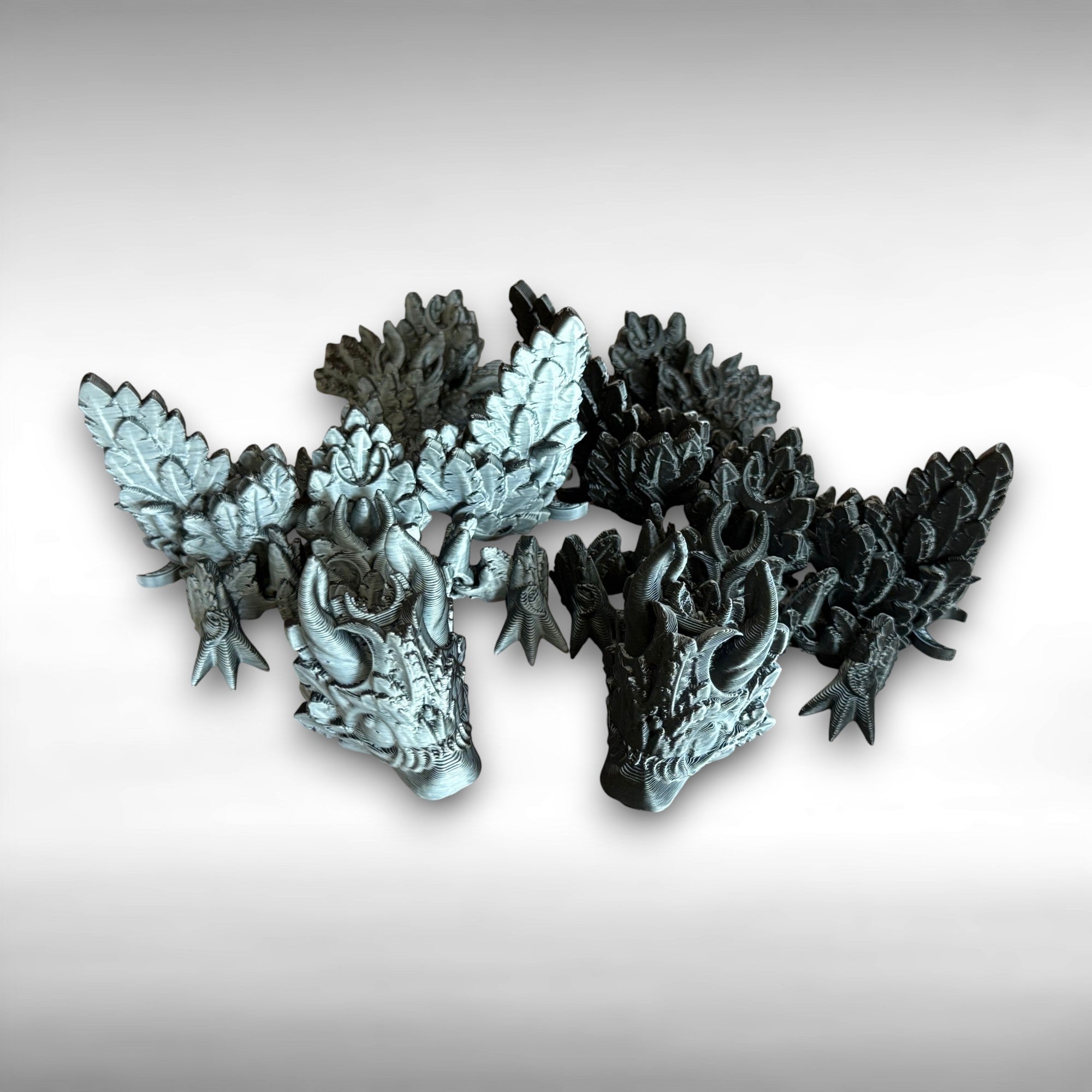 Two 3D printed black and white dragons, one primarily black and one primarily white, featuring moon shapes and wings against a white background