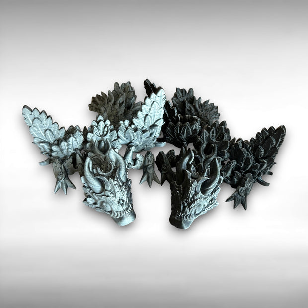 Two 3D printed black and white dragons, one primarily black and one primarily white, featuring moon shapes and wings against a white background