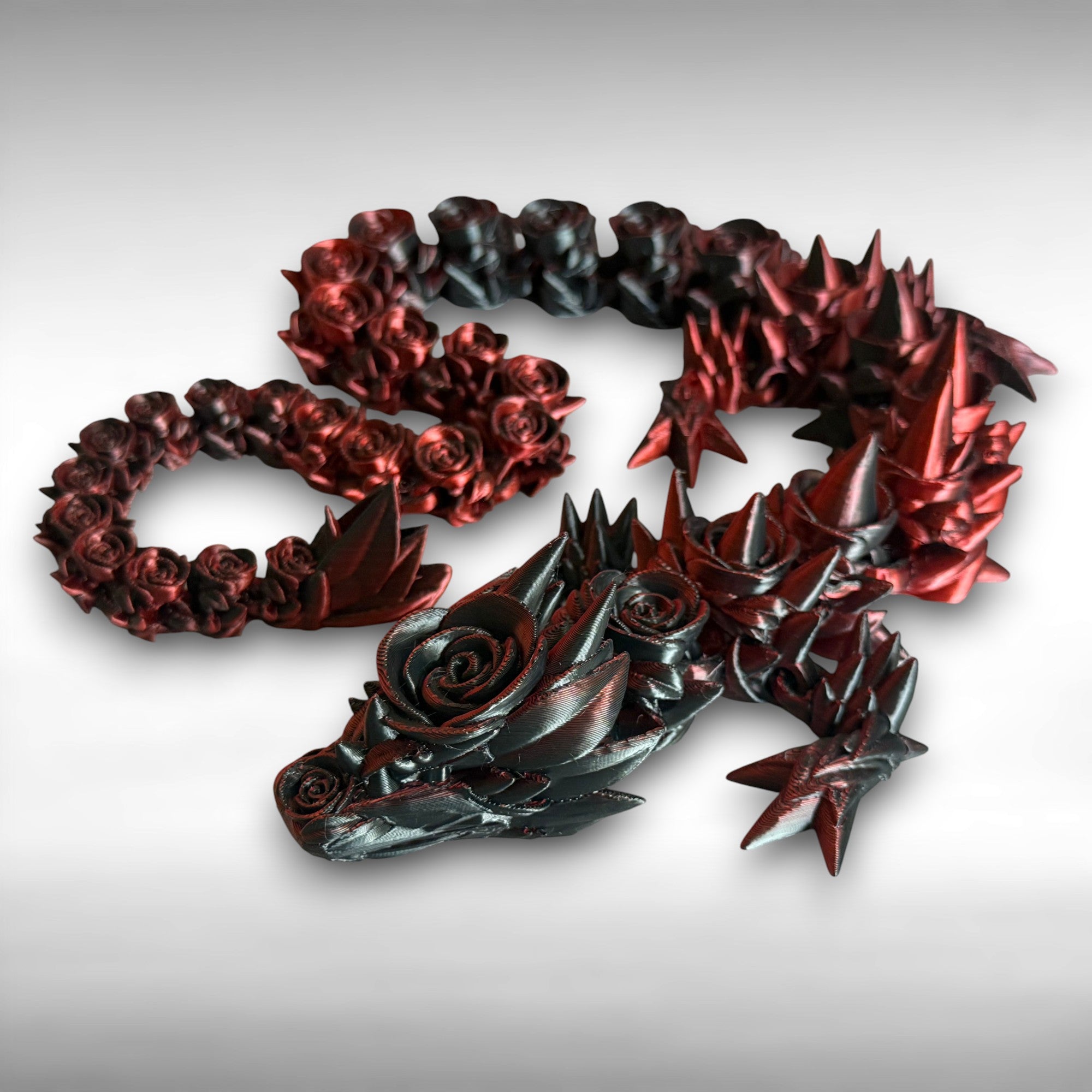 3D printed red and black dragon with rose and spike design on a gray background