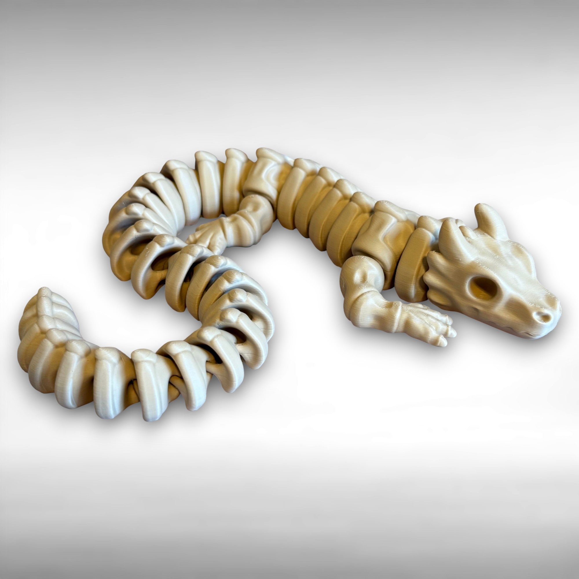 3D printed beige dragon skeleton toy against a white background