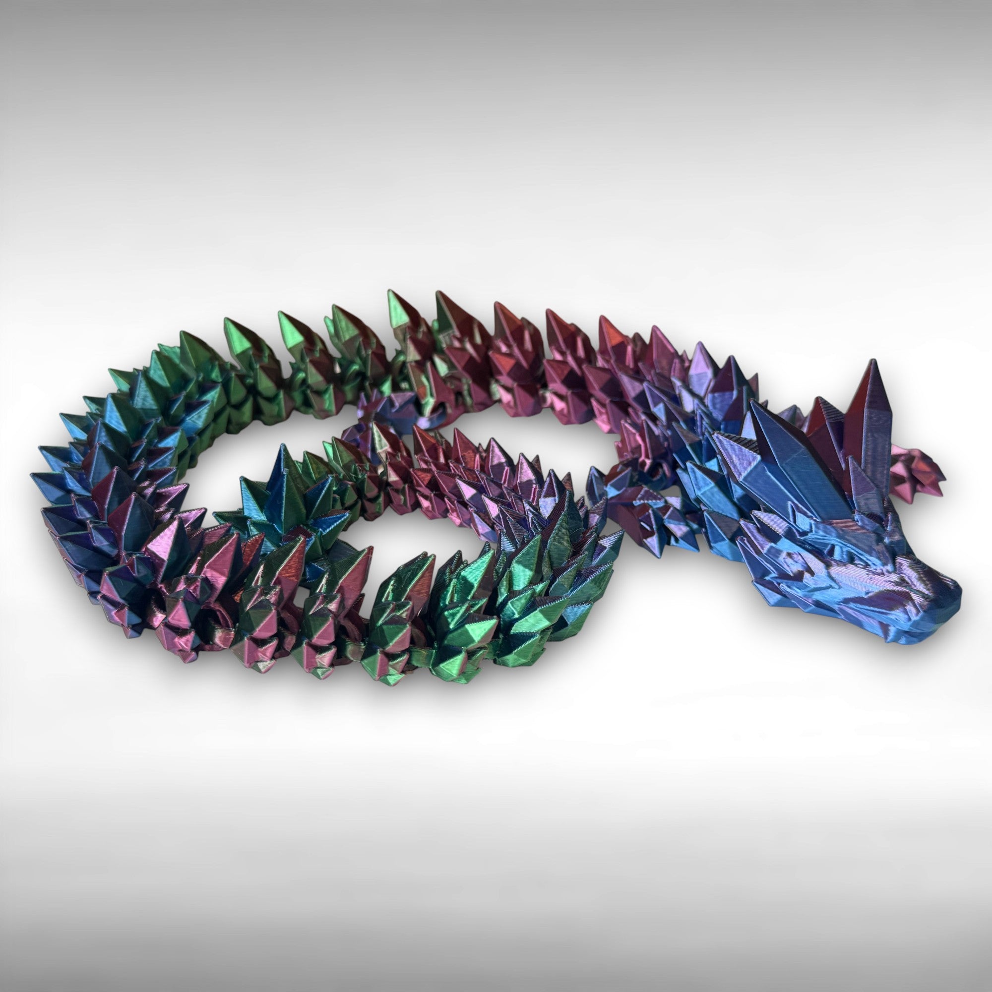 Multicolored 3D printed dragon with crystal-shaped features across the entire body against a white background