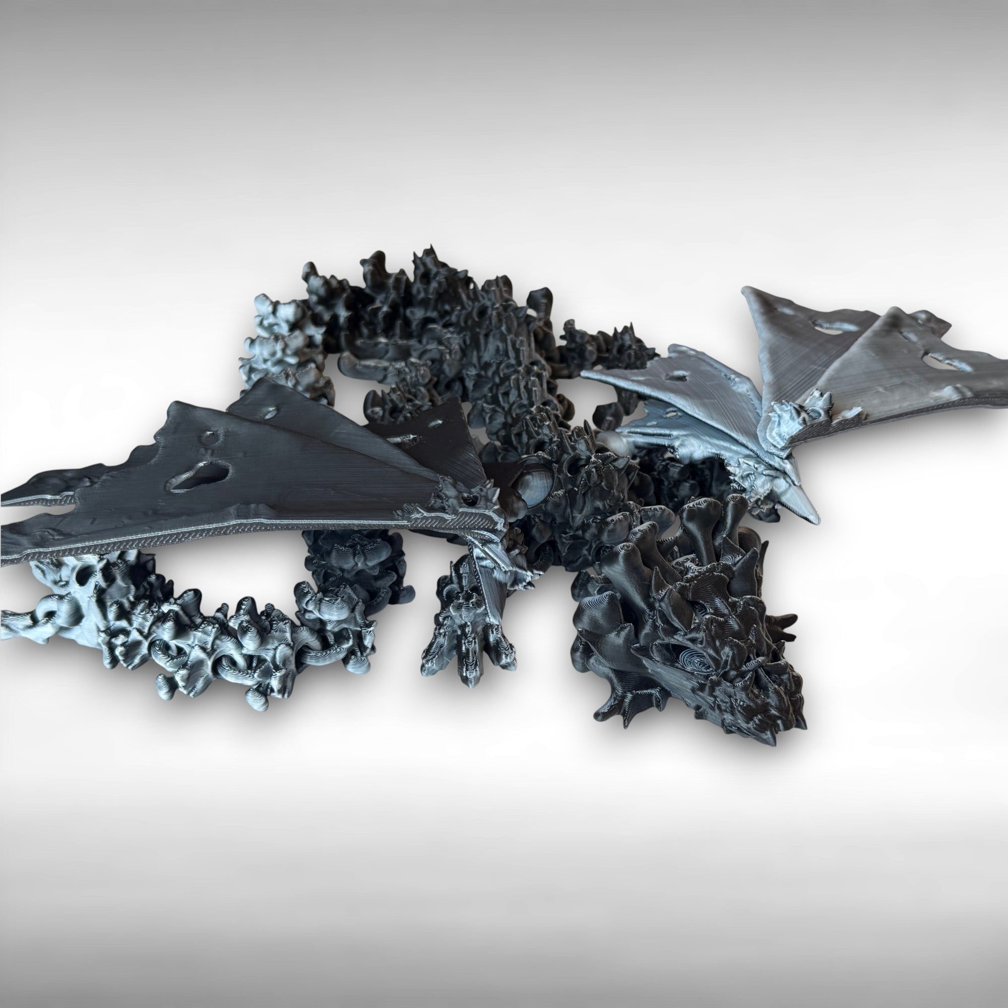 Winged black and white 3d printed dragon with a hollow theme consisting of skulls and bone-like features against a white background