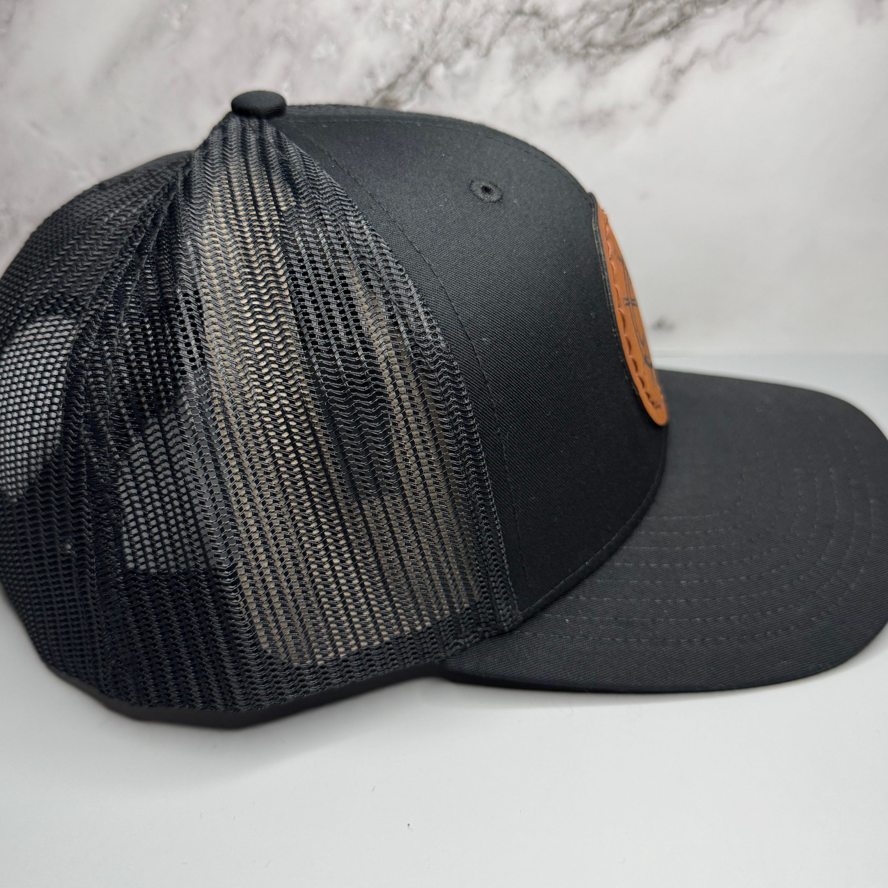 Black mesh cap with a leather patch on a light gray background