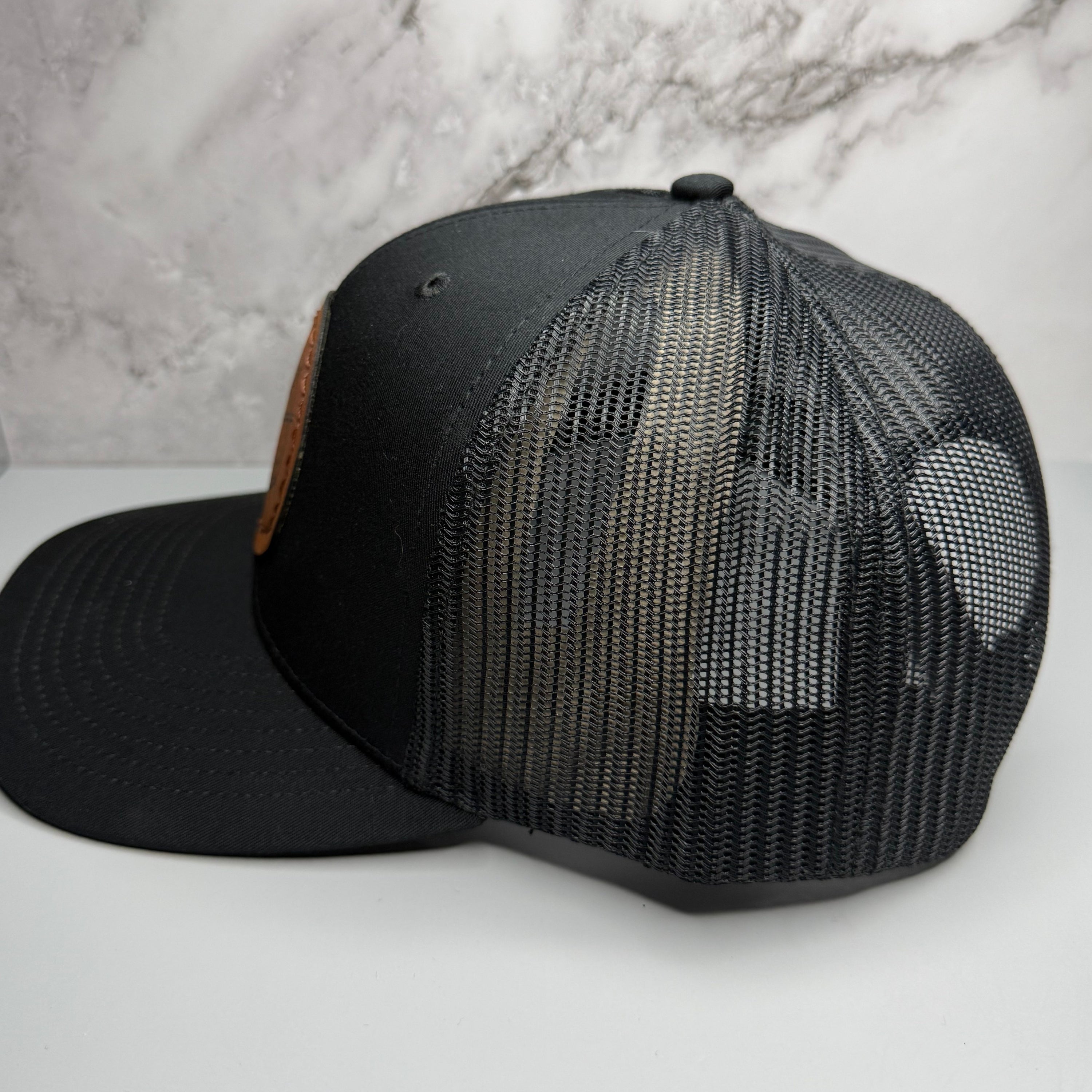 Black mesh cap with leather patch on a marble background