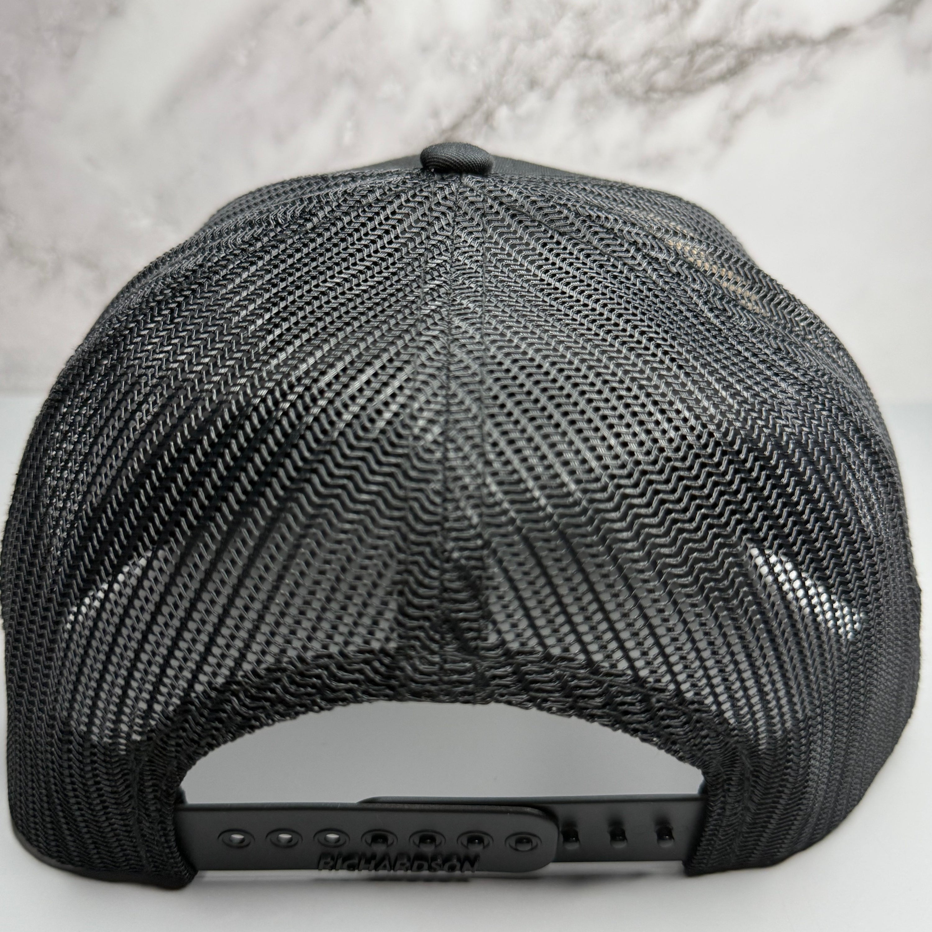Black mesh cap on a light gray textured background