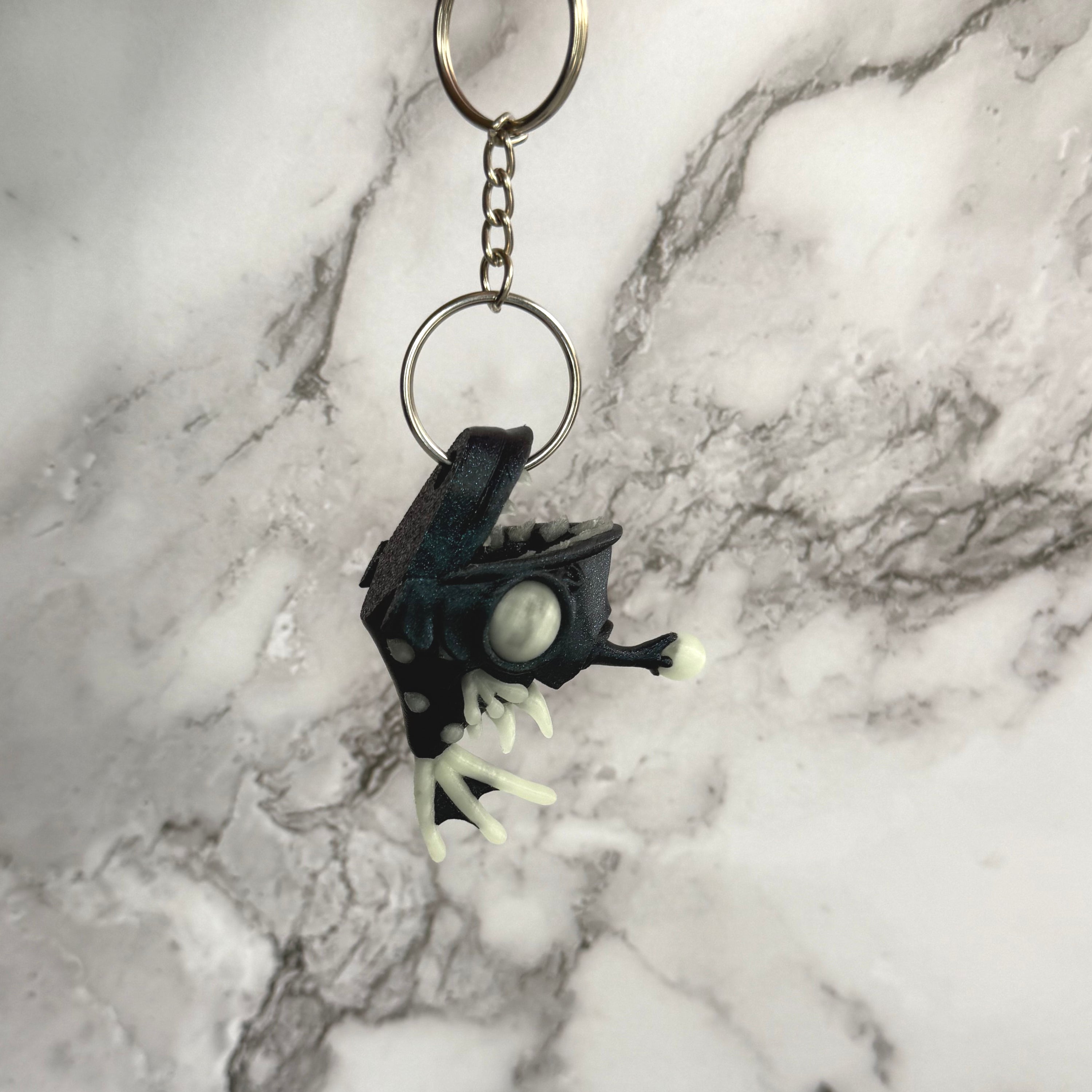 Sparkly blue angler fish keychain with white accents on a black and gray background