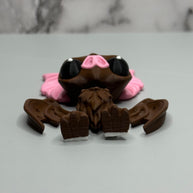 Bottom side of a figure of a brown bat with pink ears and nose on a gray and marble gray background