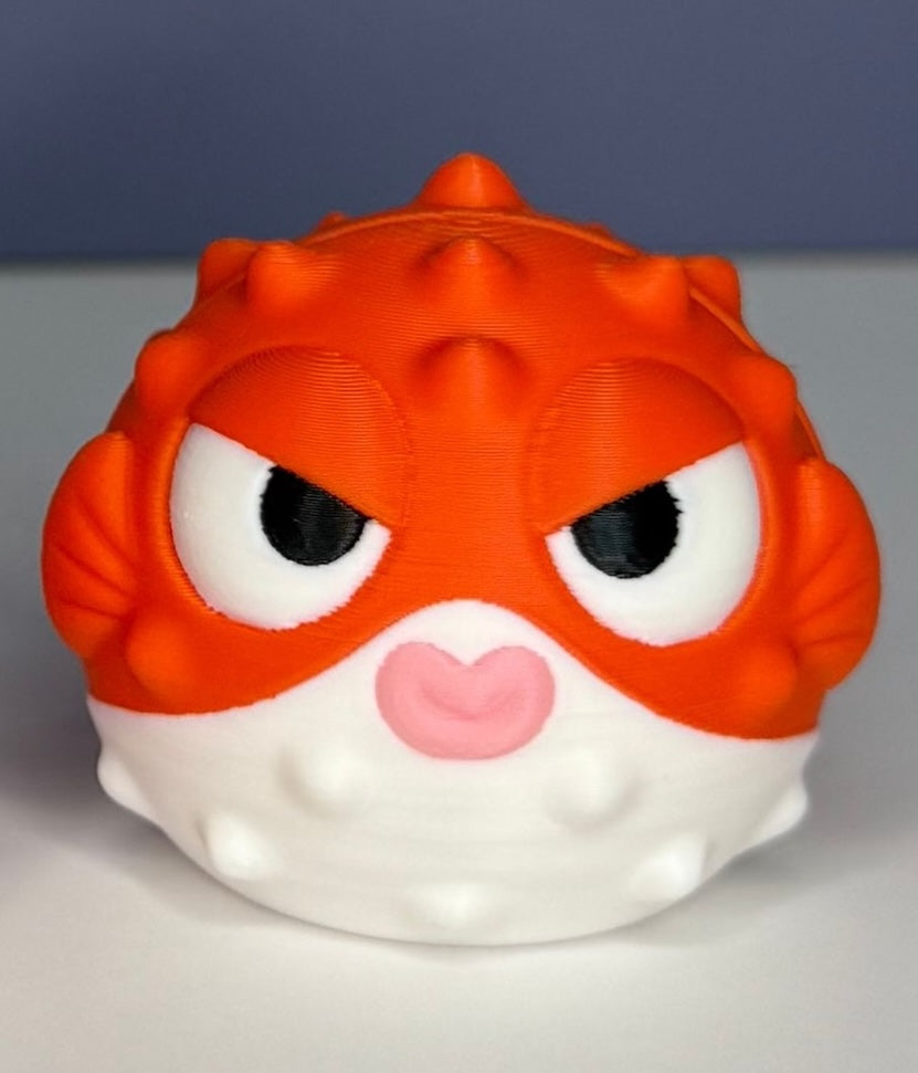 Orange and white puffer fish figure with slanted eyes on a white and blue background