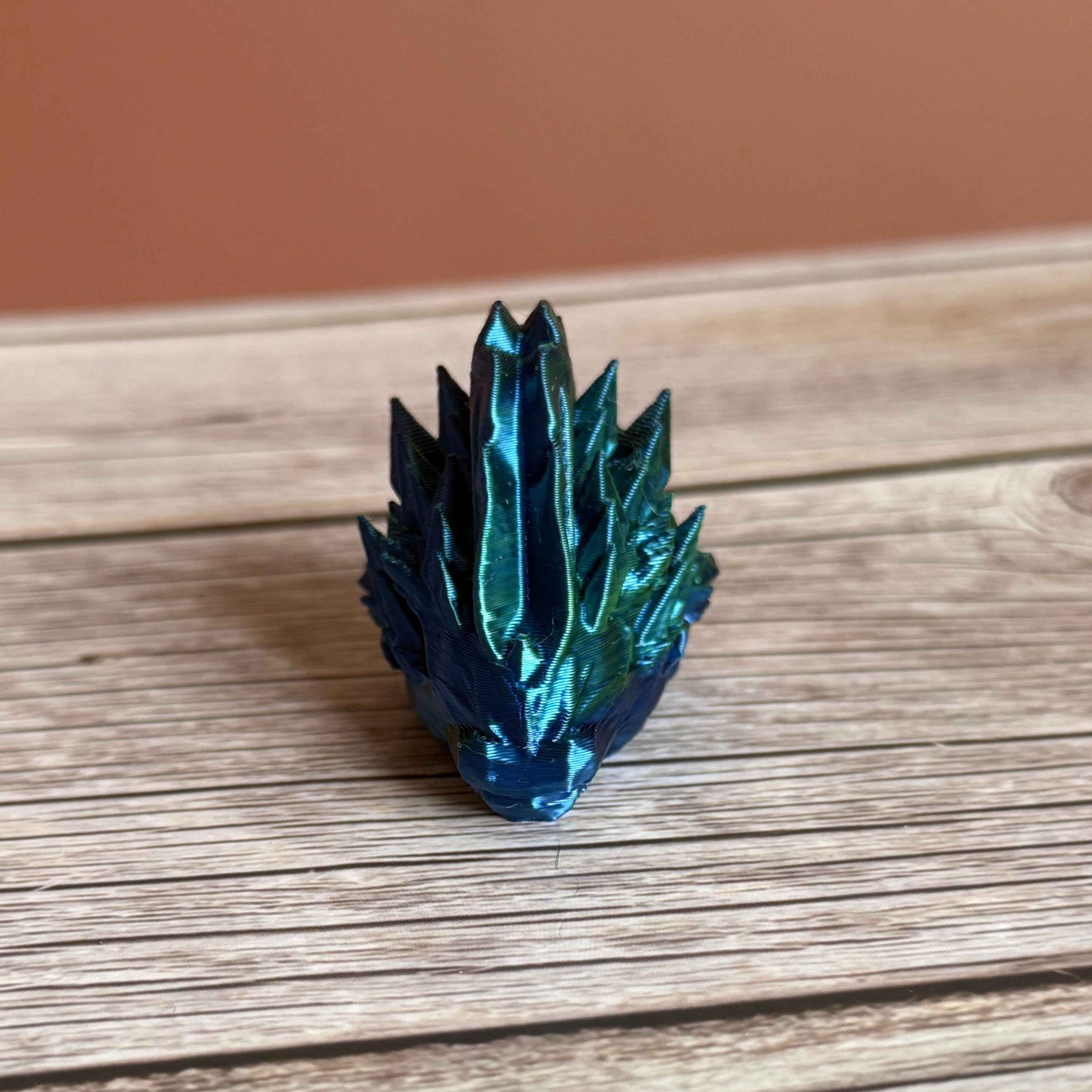 3D printed blue and green jellyfish-themed dragon head keychain, placed on a wooden surface