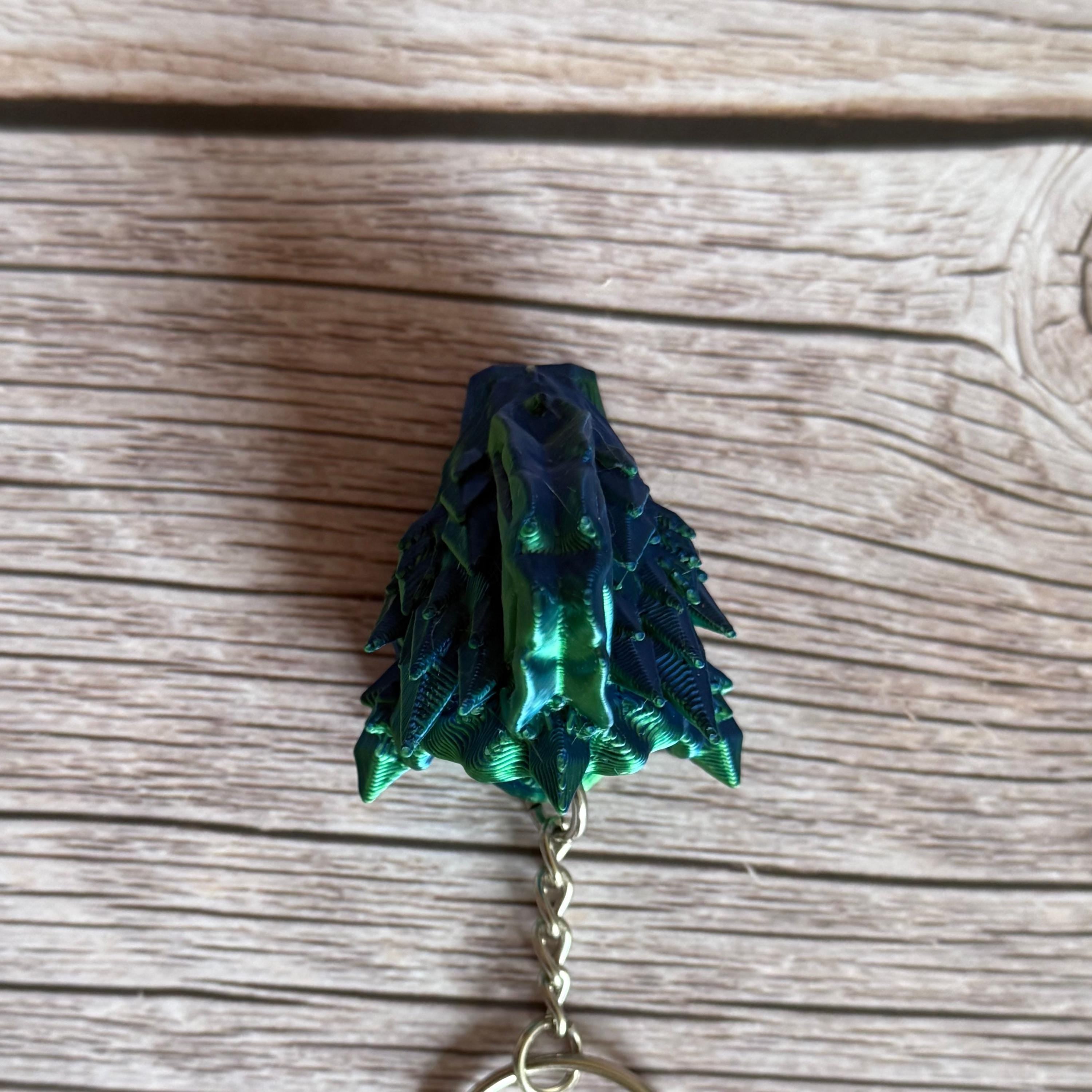 Top of a 3D printed blue and green jellyfish-themed dragon head keychain, placed on a wooden surface