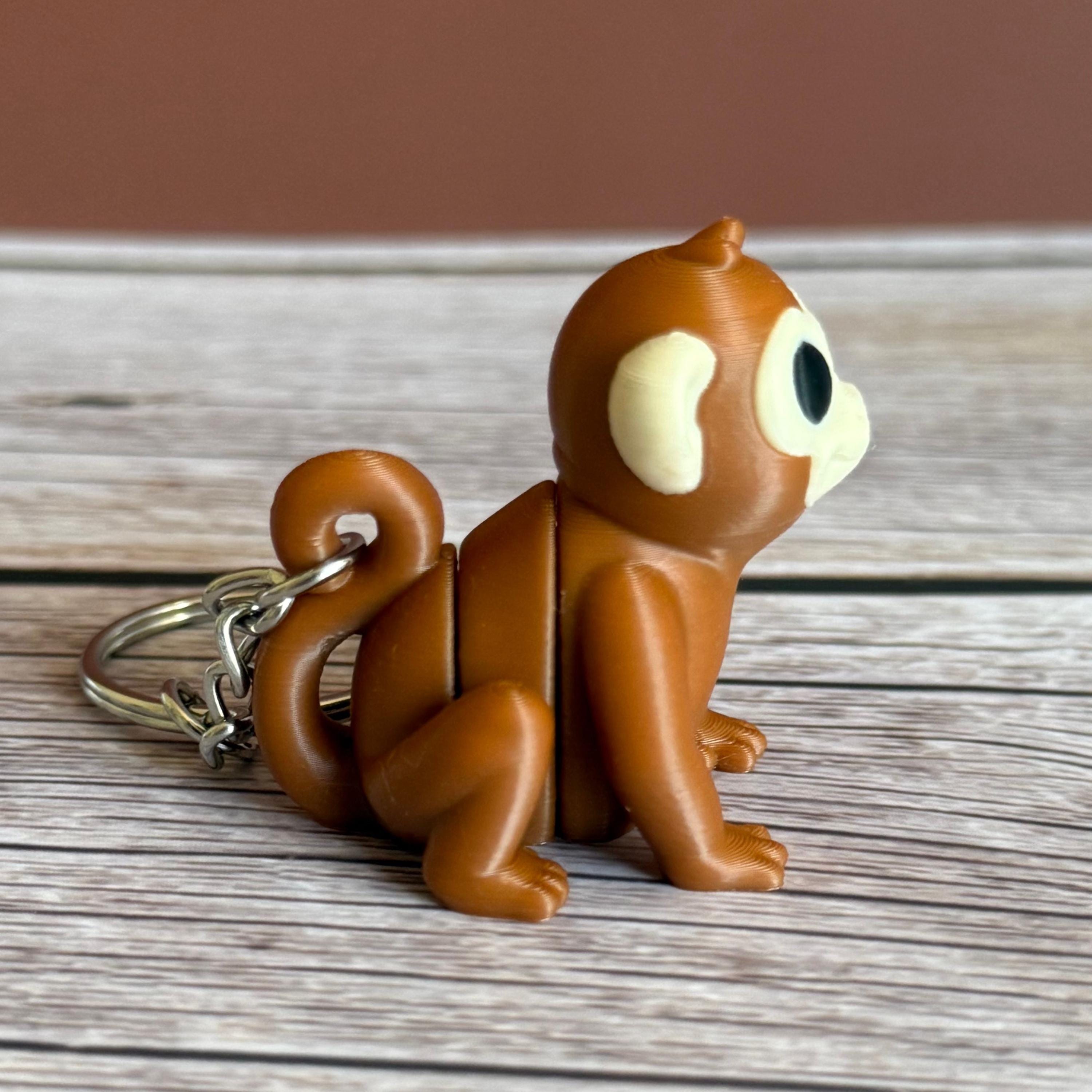 Side of a 3D printed brown monkey-shaped keychain on a wooden surface
