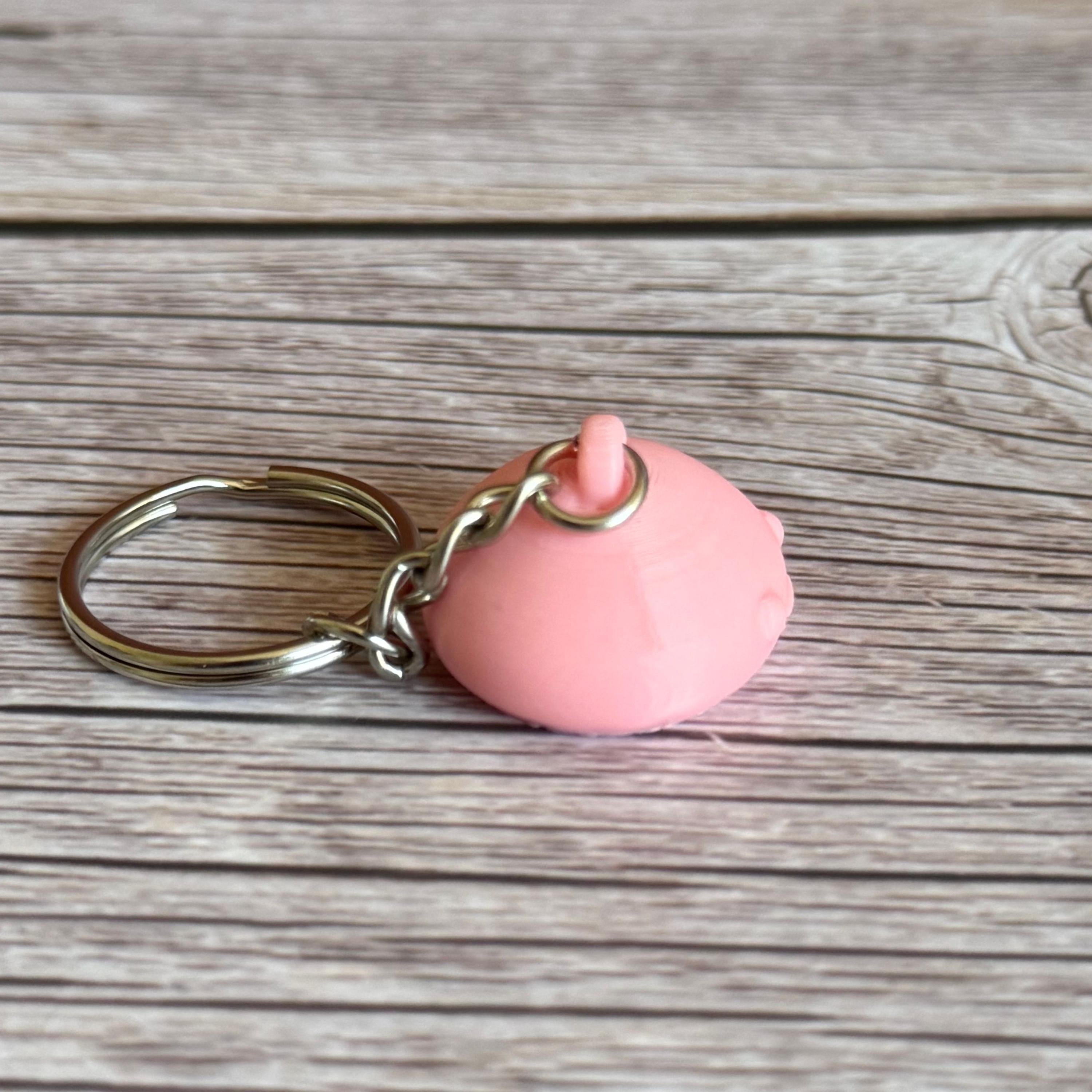 3D Printed pink jellyfish-like keychain with body hidden inside head on a wooden surface