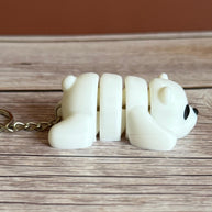Side of a 3D printed white bear-shaped keychain on a wooden surface