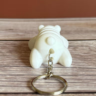 Back of a 3D printed white bear-shaped keychain on a wooden surface