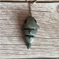 Top of a 3D printed gray catfish-shaped keychain on a wooden surface