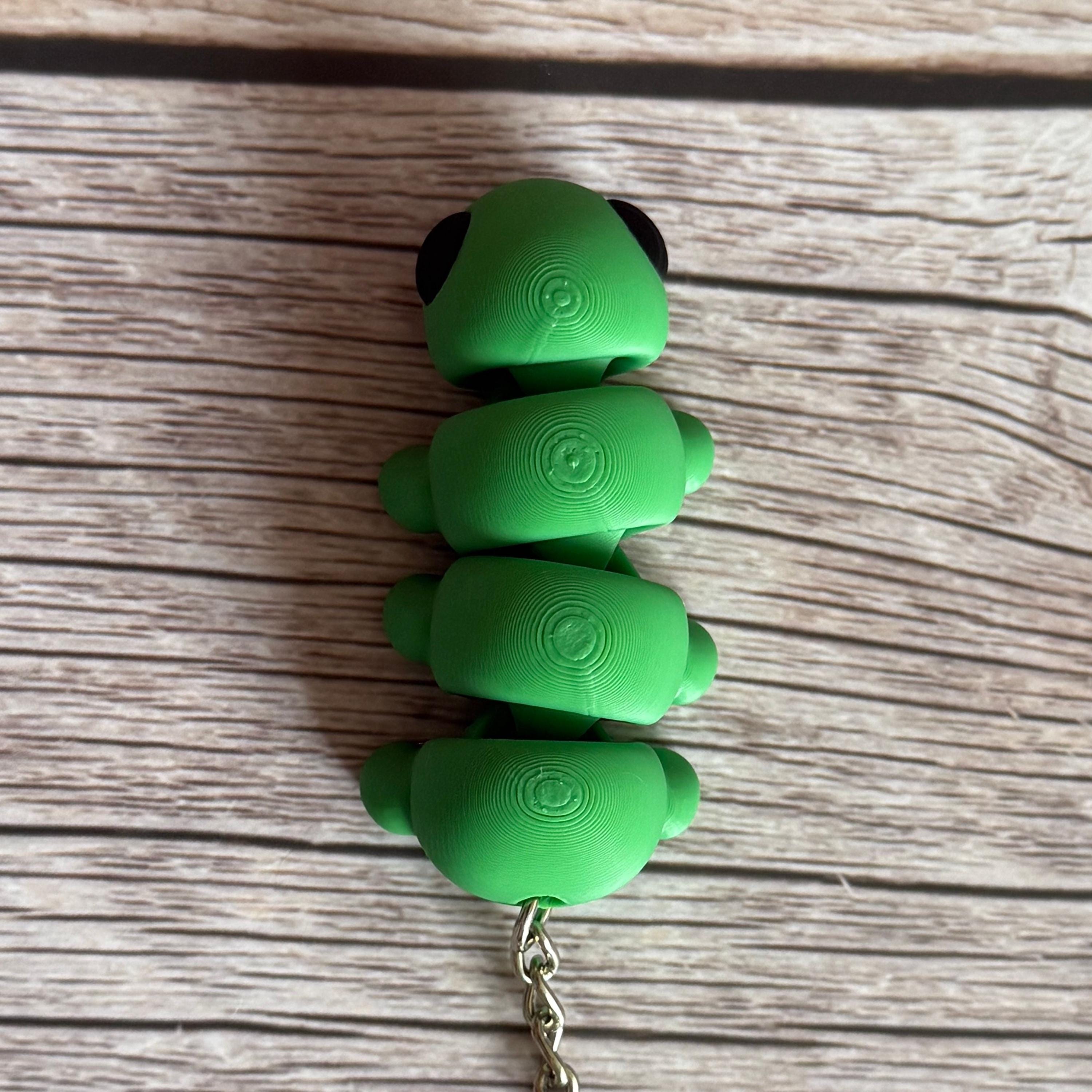 Top of a 3D printed green caterpillar-shaped keychain on a wooden surface