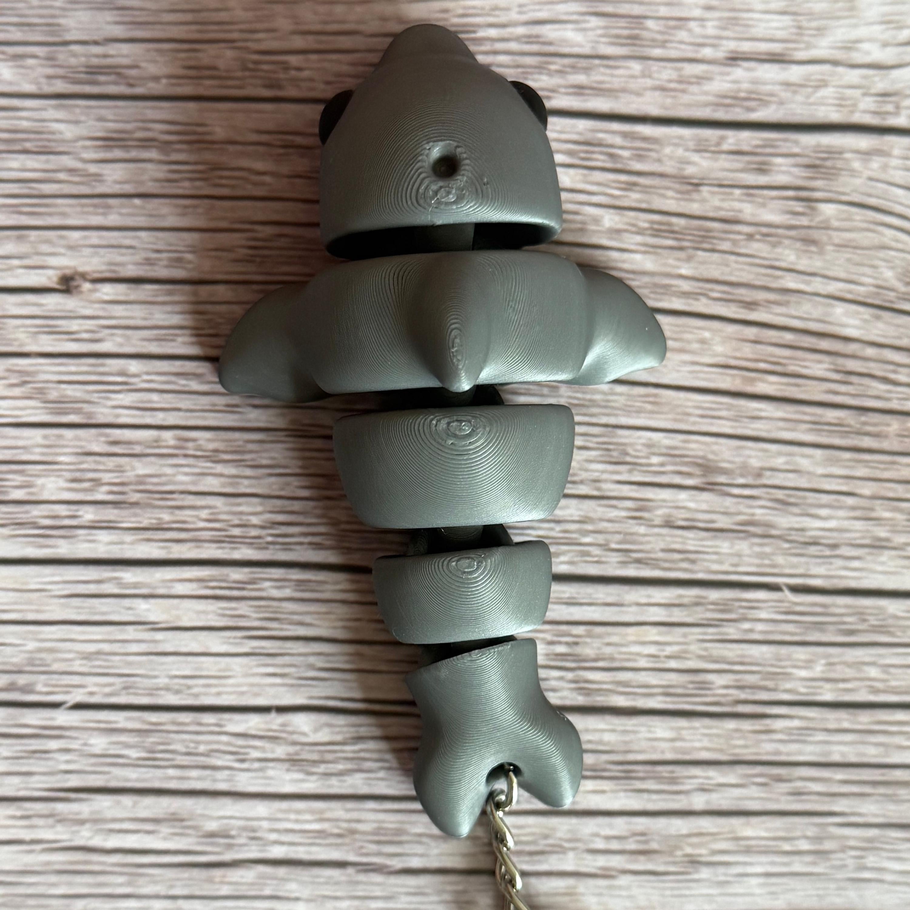 Top of a 3D printed gray dolphin-shaped keychain on a wooden surface