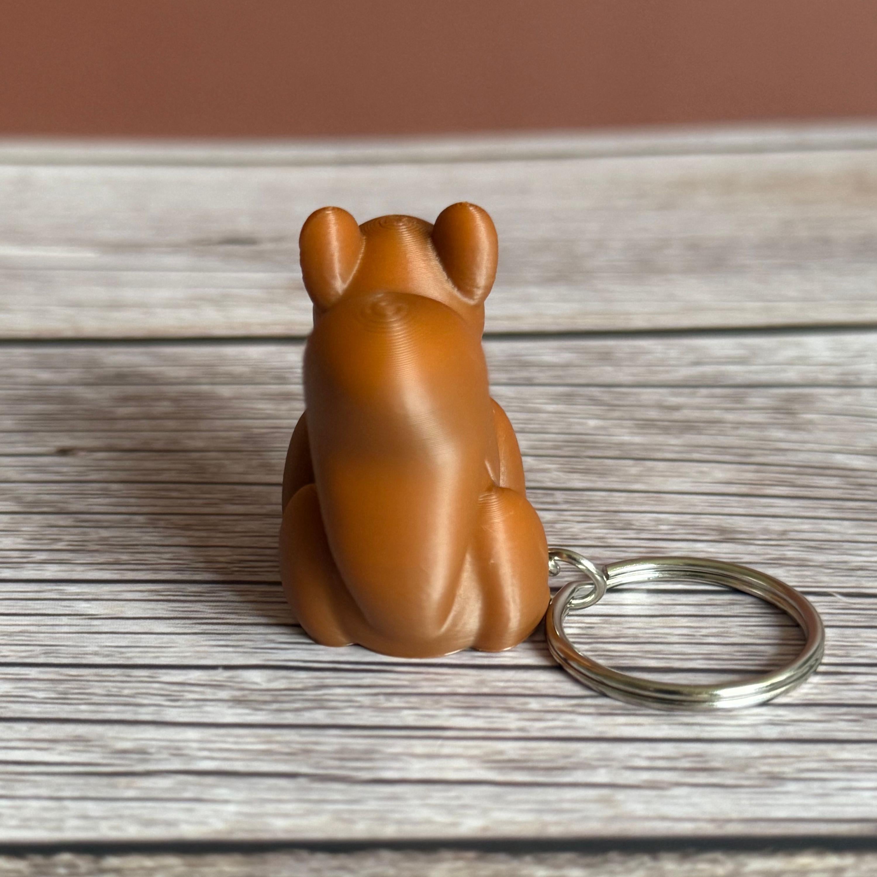 Back of a 3D printed brown squirrel-shaped keychain on a wooden surface
