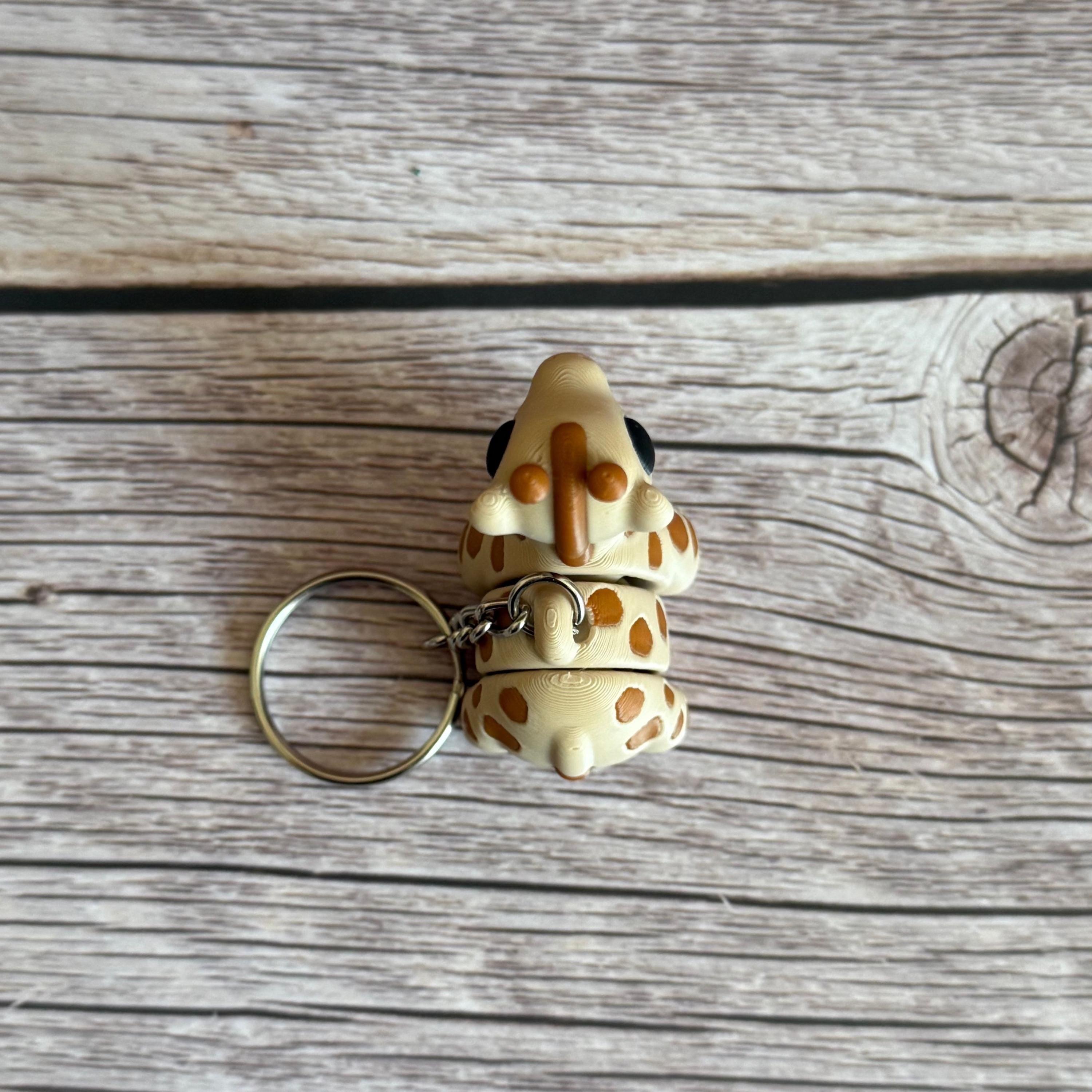 Top of 3D printed beige and brown giraffe-shaped keychain, placed on a wooden surface