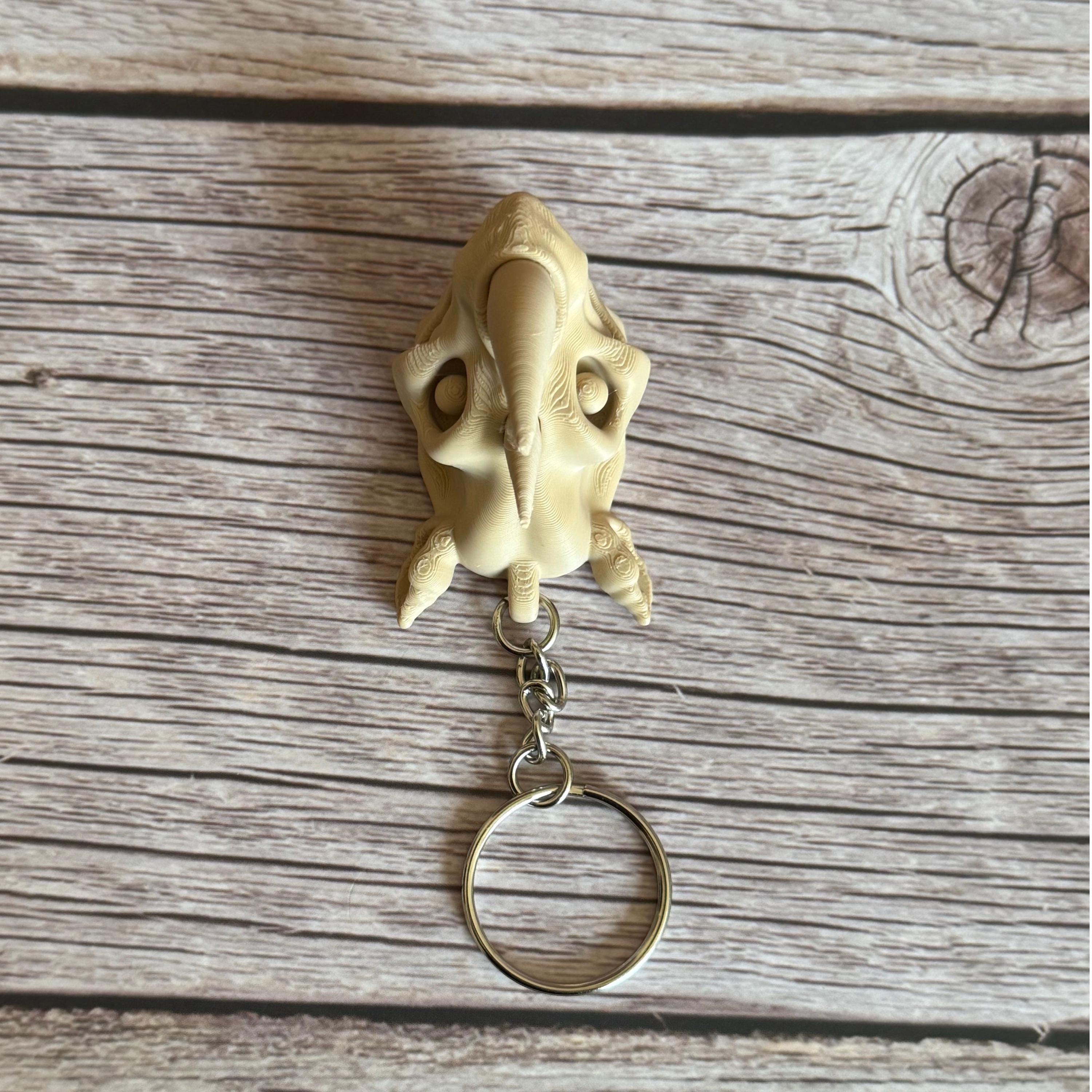 3D printed beige rhino skull keychain, placed on a wooden surface