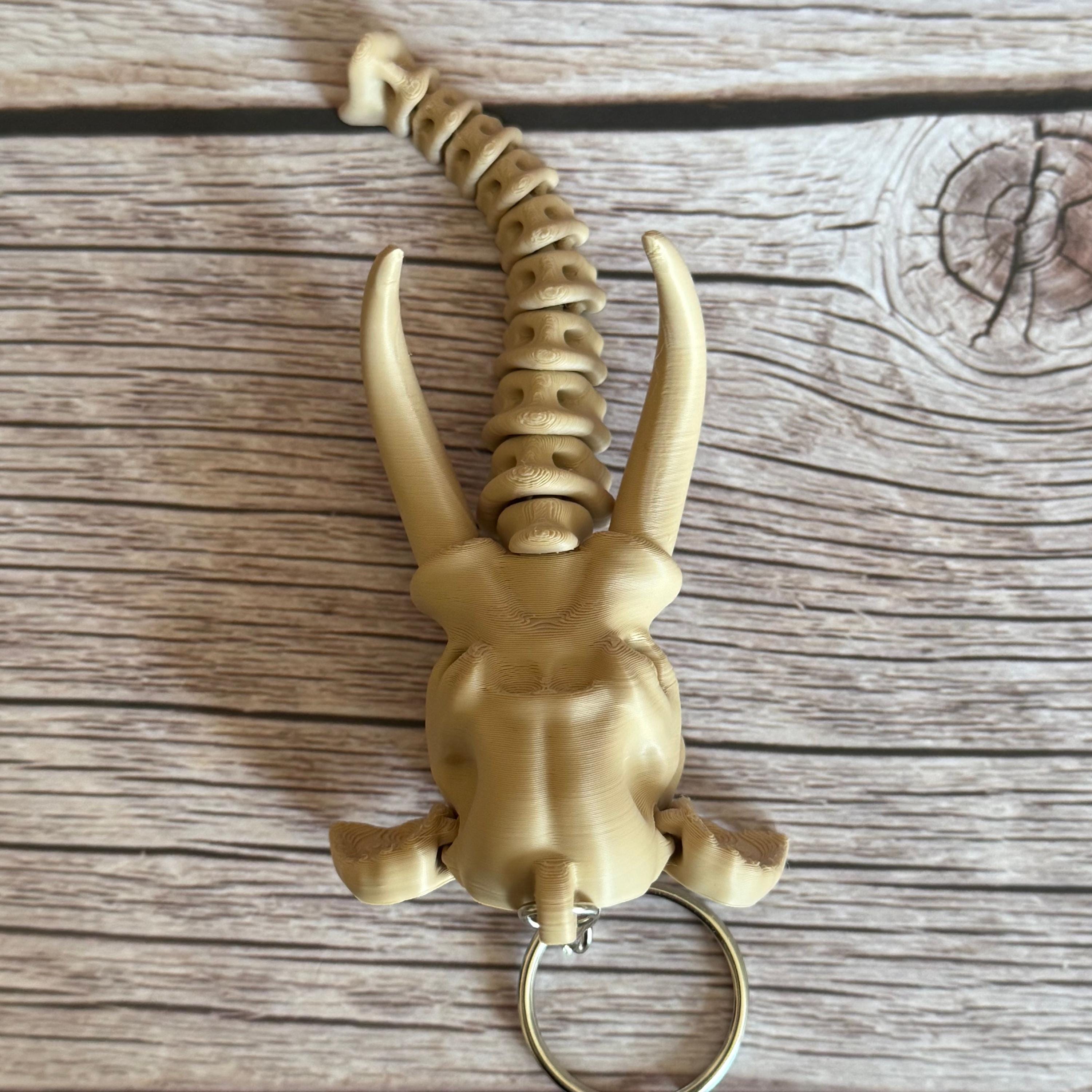 top of 3D printed beige elephant skull with articulated skeleton-like trunk, placed on a wooden surface