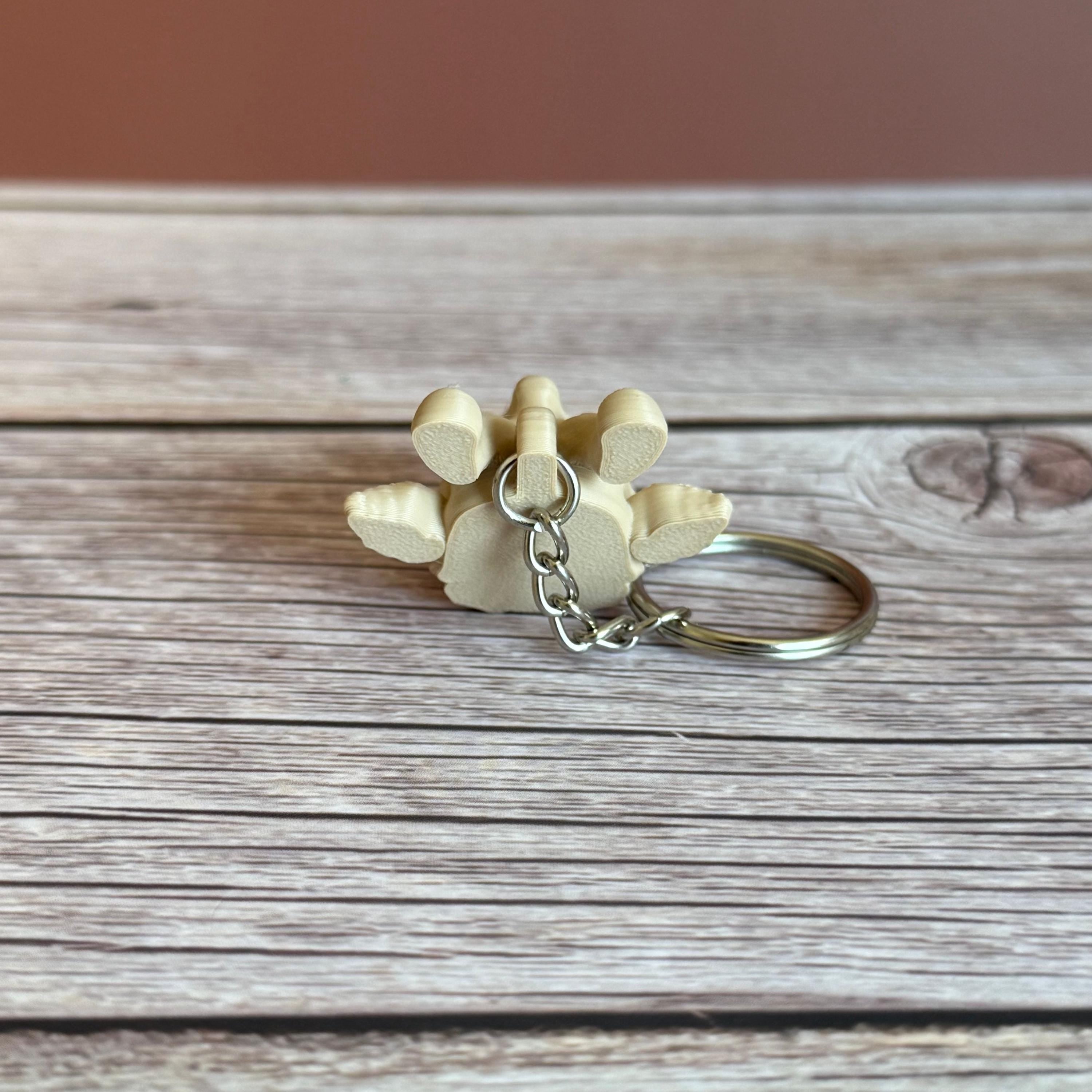 back of 3D printed beige giraffe skull keychain, placed on a wooden surface and brown background