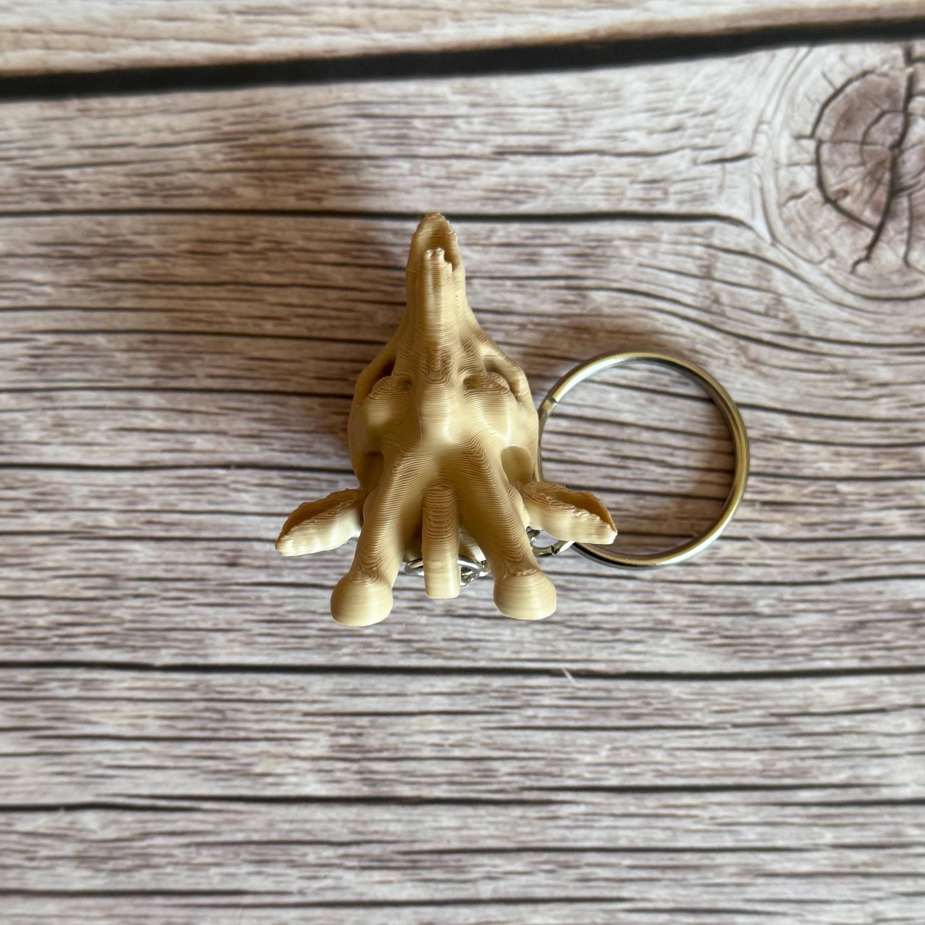 top of 3D printed beige giraffe skull keychain, placed on a wooden surface 
