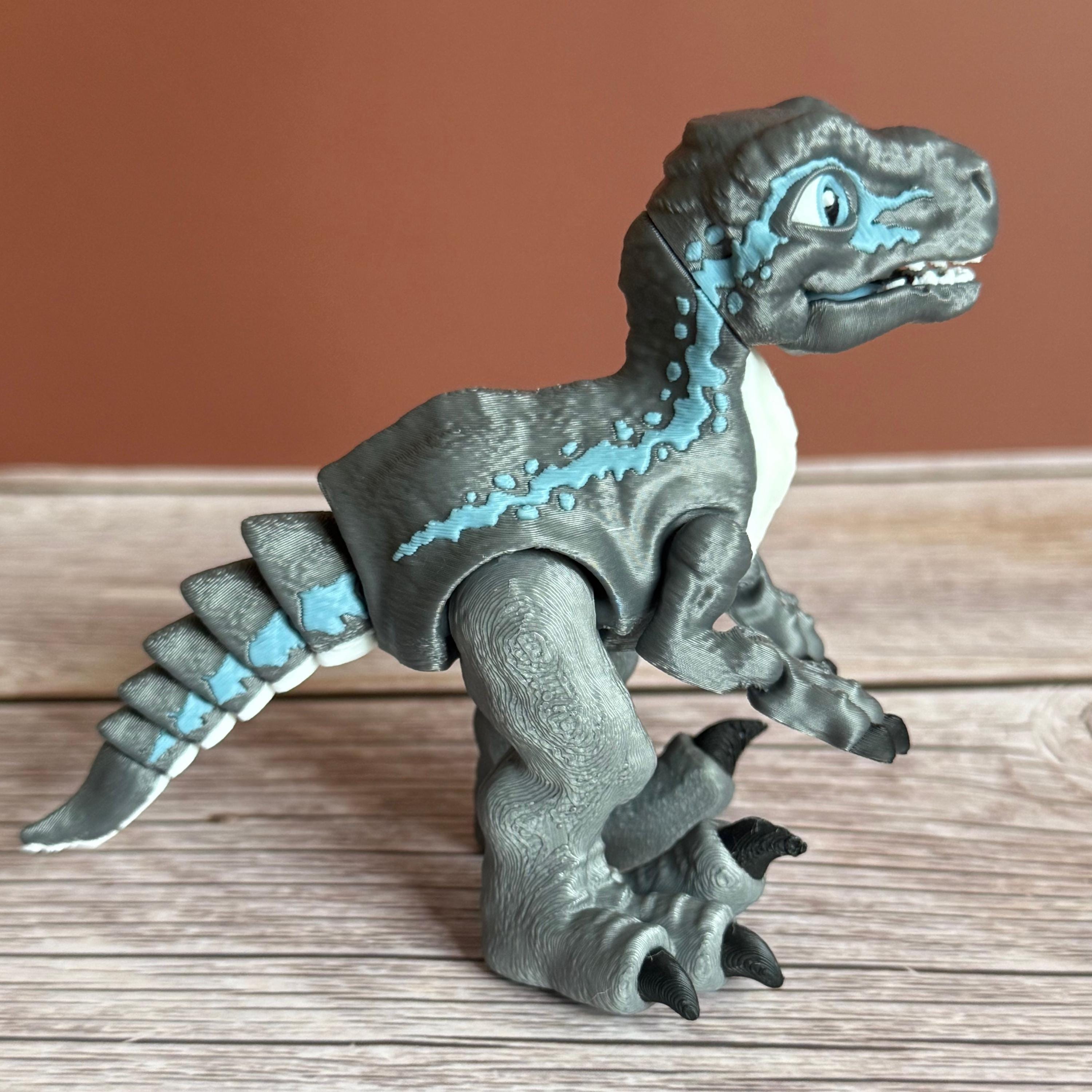 Side of a 3D printed blue, gray, and white colored raptor dinosaur figure, placed on a wooden surface against a brown background