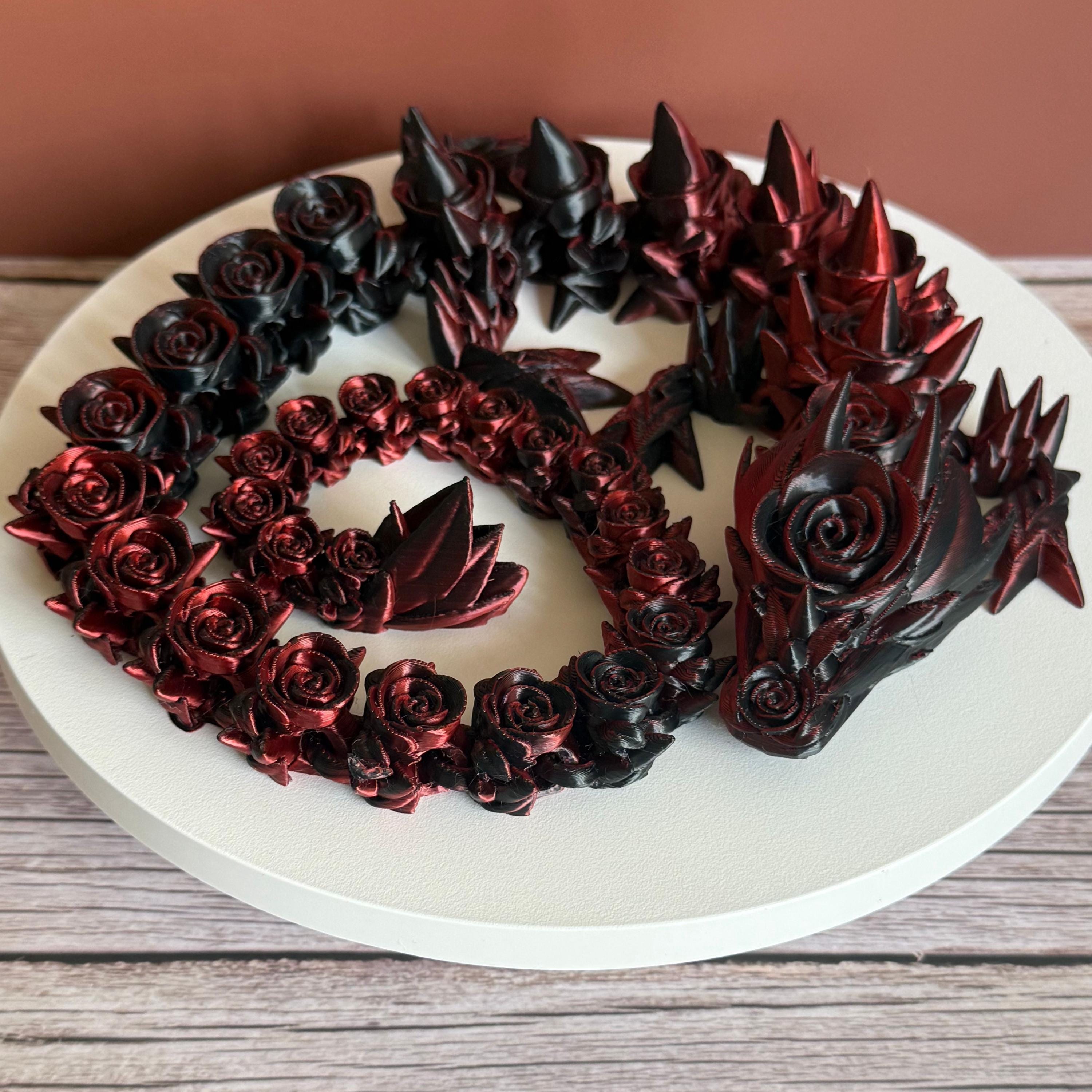 Top of 3D printed red and black dragon with rose and spike design on a white surface