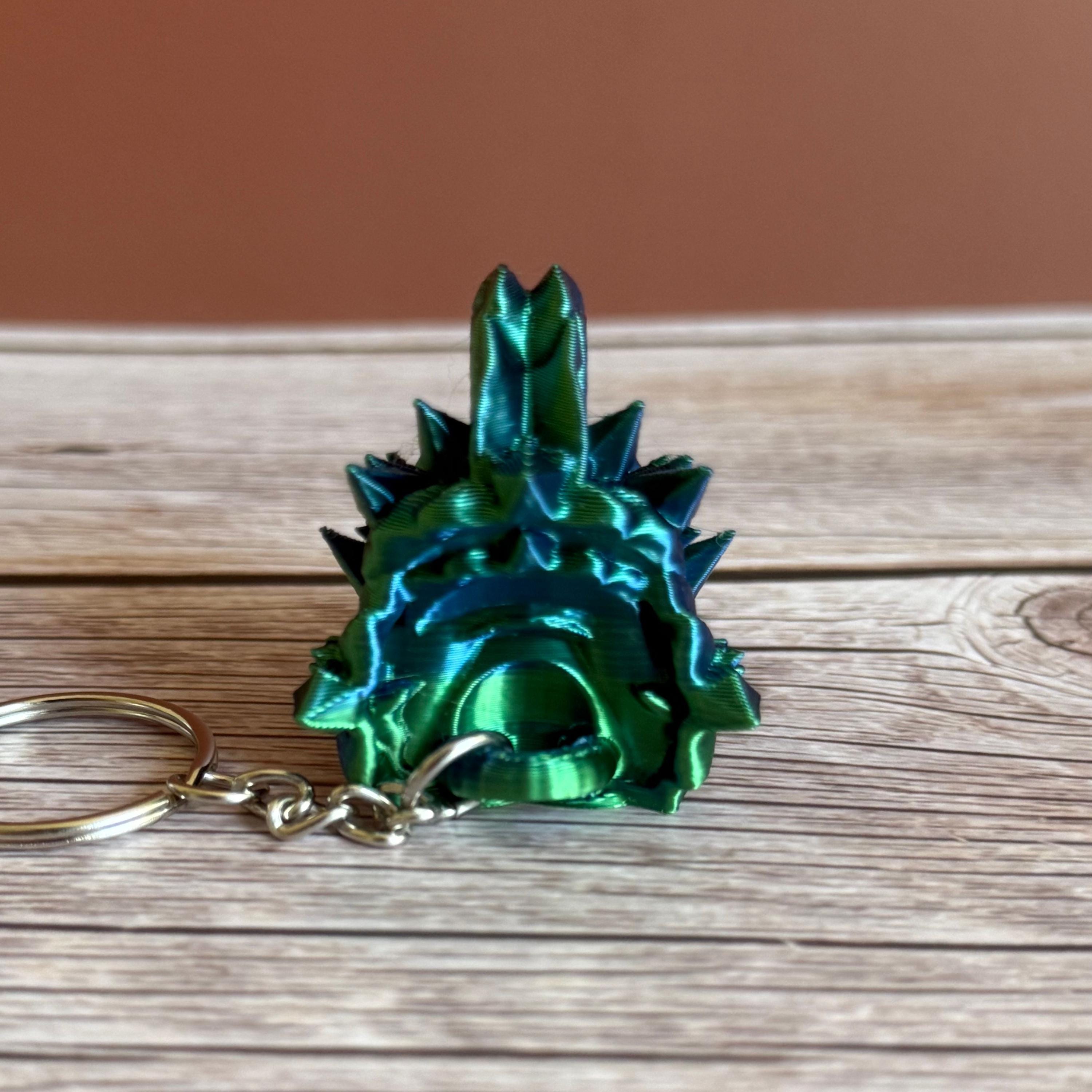 Back of a 3D printed blue and green jellyfish-themed dragon head keychain, placed on a wooden surface