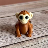 3D printed brown monkey-shaped keychain on a wooden surface