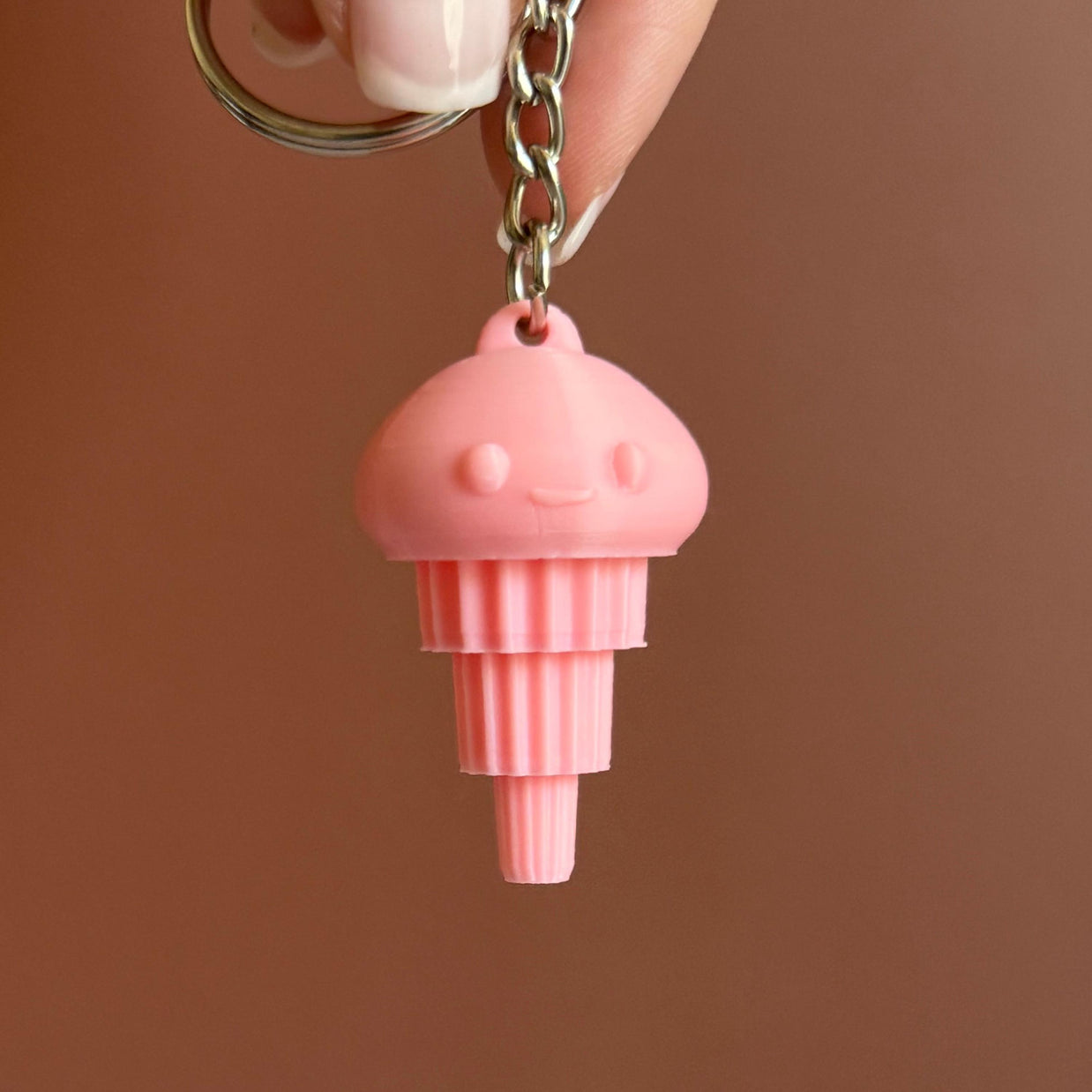 A 3D printed pink articulated jellyfish keychain attached to a keyring, displayed against a brown background.