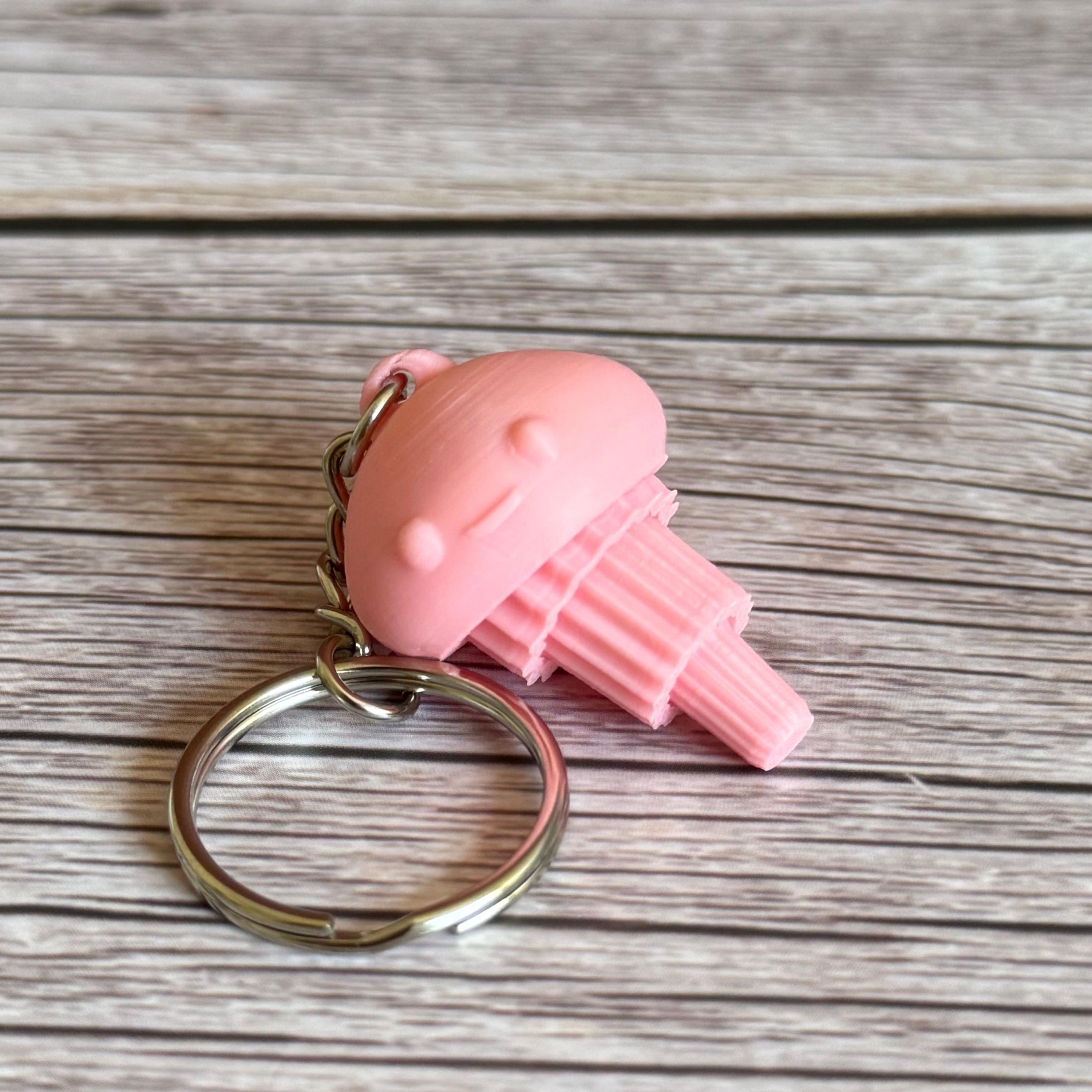 3D Printed pink jellyfish-like keychain with a smiling face on a wooden surface