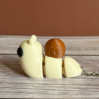 Side of a 3D printed beige and brown snail-shaped keychain on a wooden surface