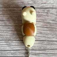 Top of a 3D printed beige and brown snail-shaped keychain on a wooden surface