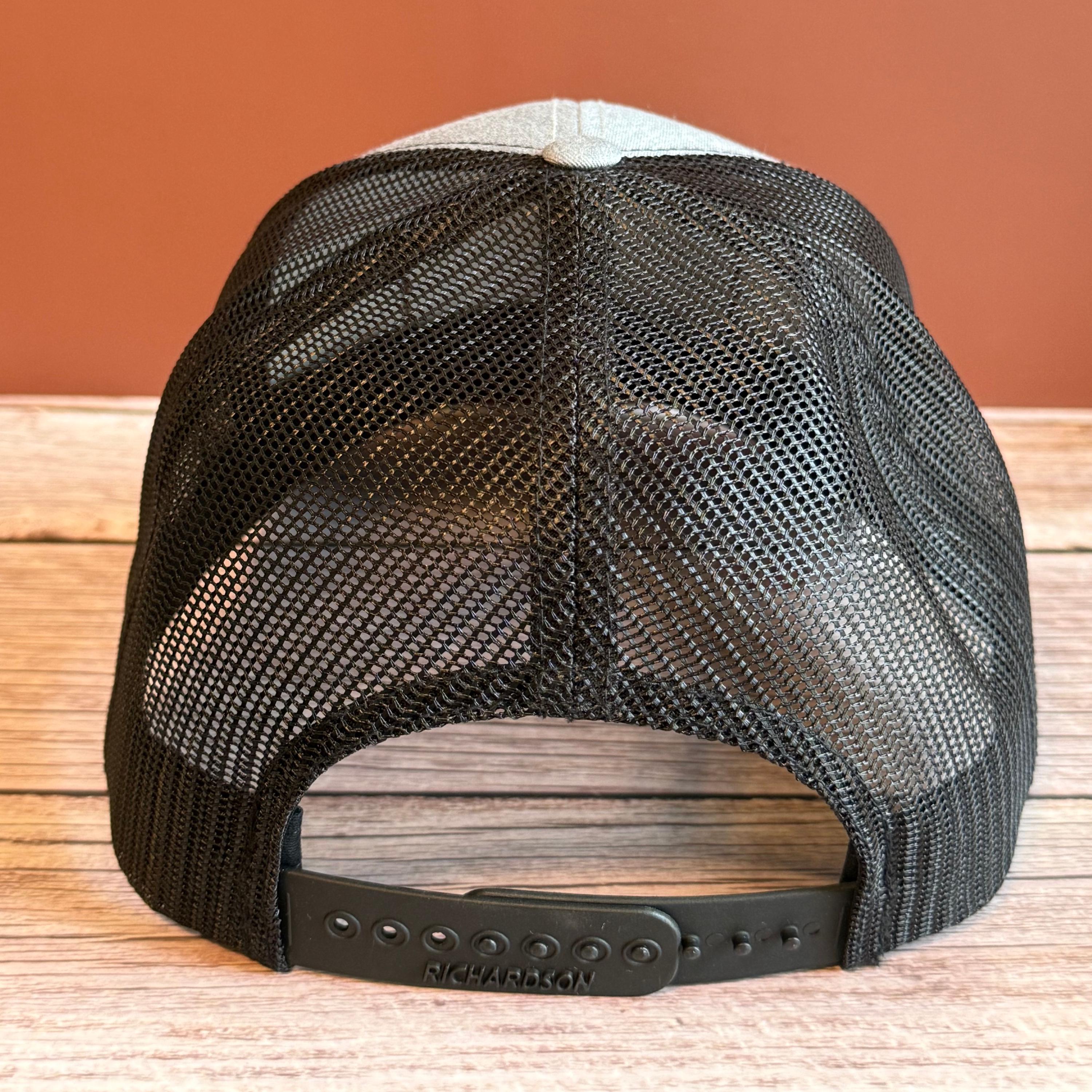 black backside of snapback hat, placed on a wooden surface against a brown background