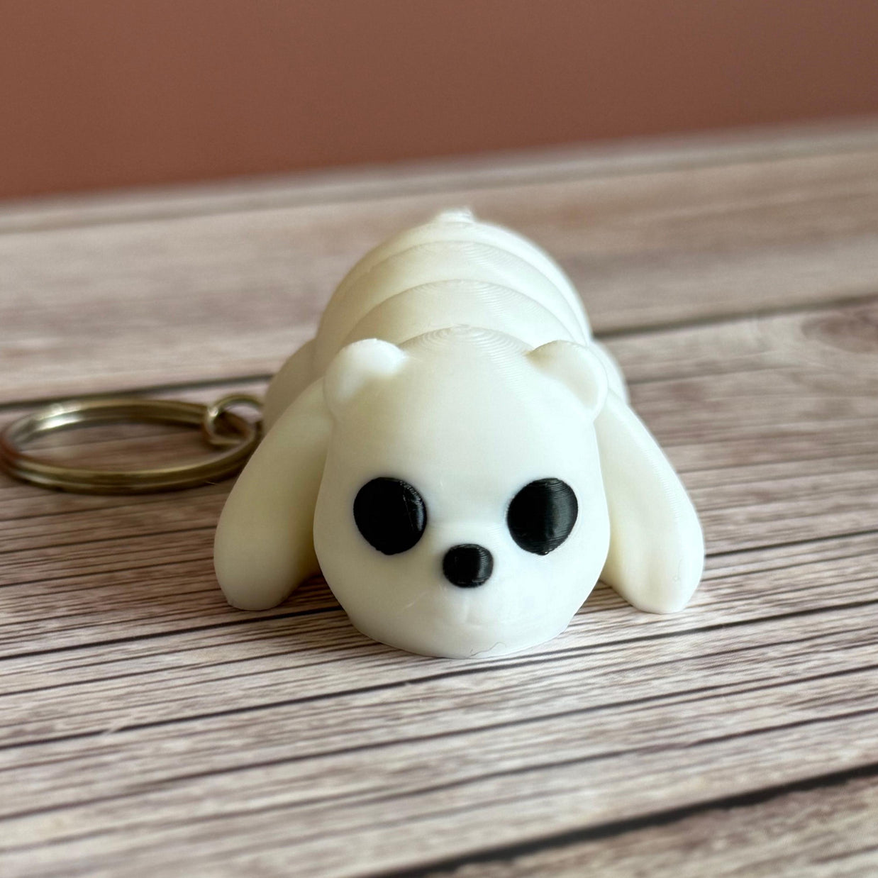 3D printed white bear-shaped keychain on a wooden surface