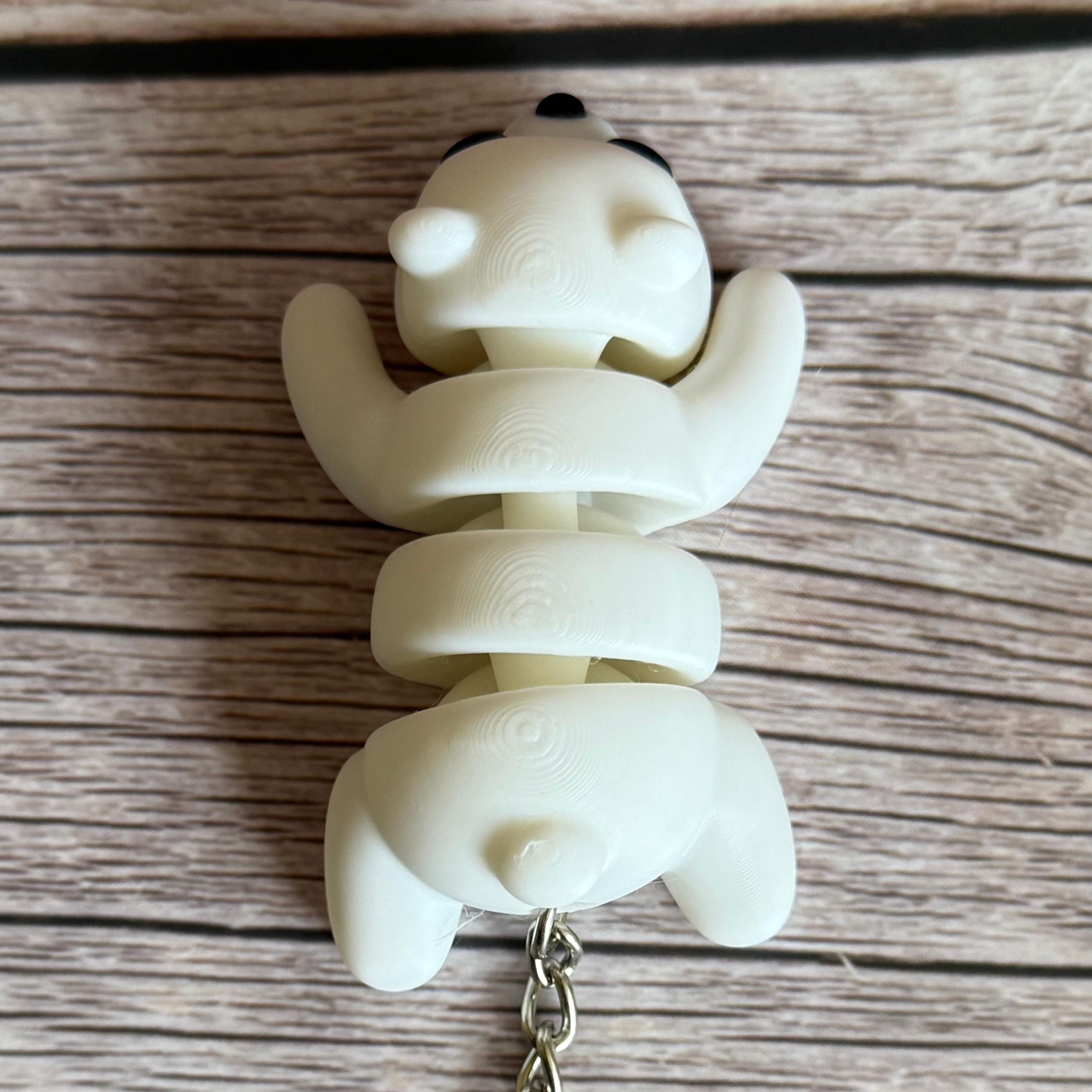 Top of a 3D printed white bear-shaped keychain on a wooden surface
